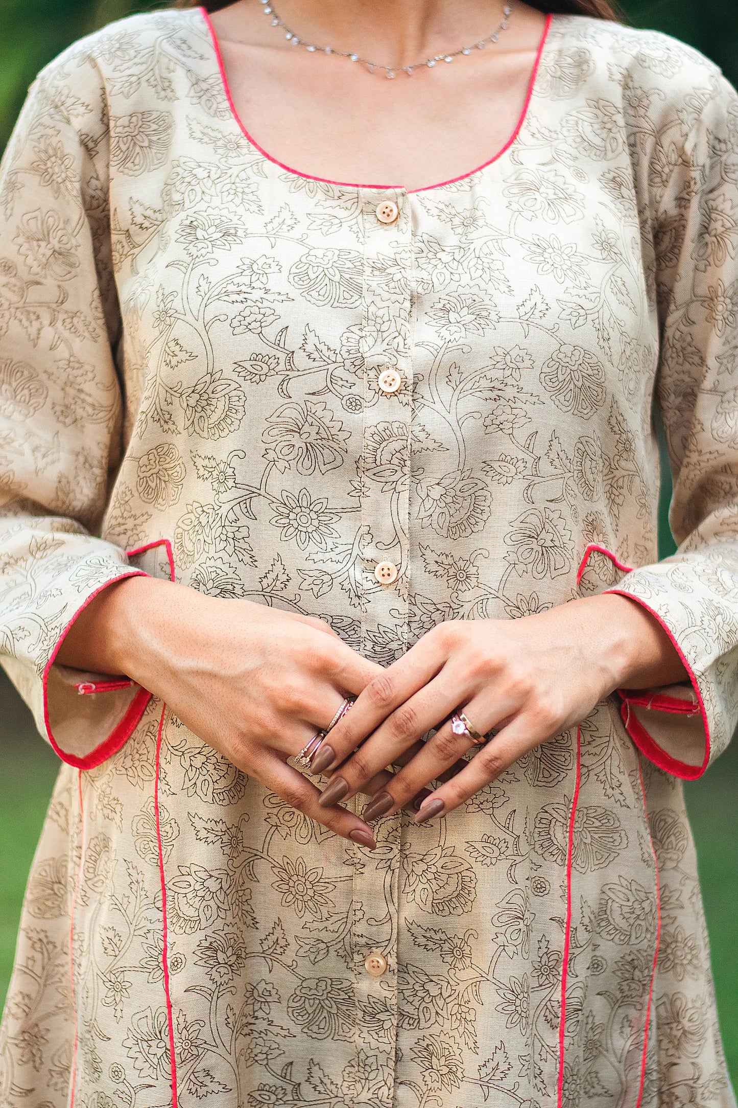 An indian woman wearing a printed staple tussar gold A line kurta. The A line kurta has double kali in red colour. The woman's left side is facing the camera and the camera has zoomed in to focus on the print of the kurta.