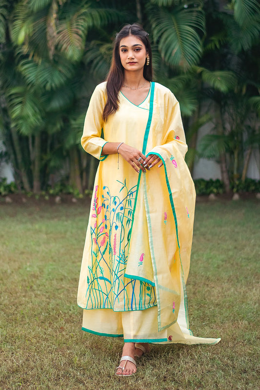 Indian model in a yellow angrakha kurta with pink and teal resham embroidery, paired with a matching dupatta and palazzo.