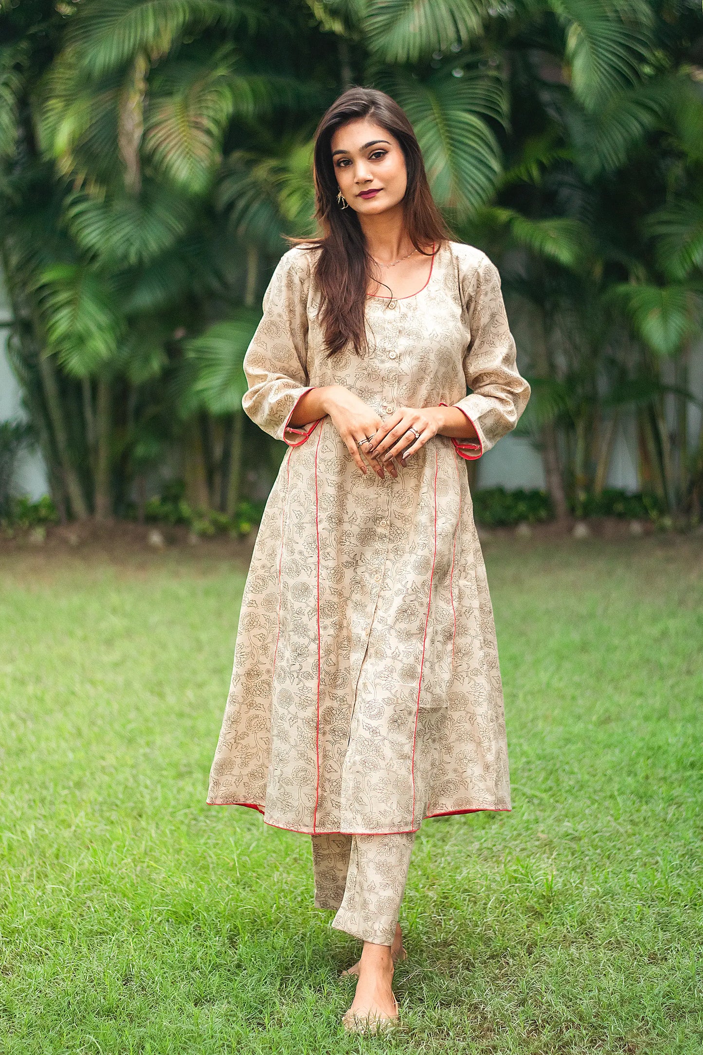 An indian woman wearing a printed staple tussar gold A line kurta and trousers. The woman looks in the camera