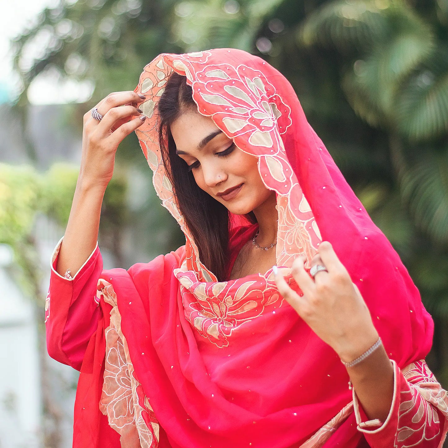Close-up of an Indian model wearing a red organza kurta with gold cutwork, paired with a matching dupatta.