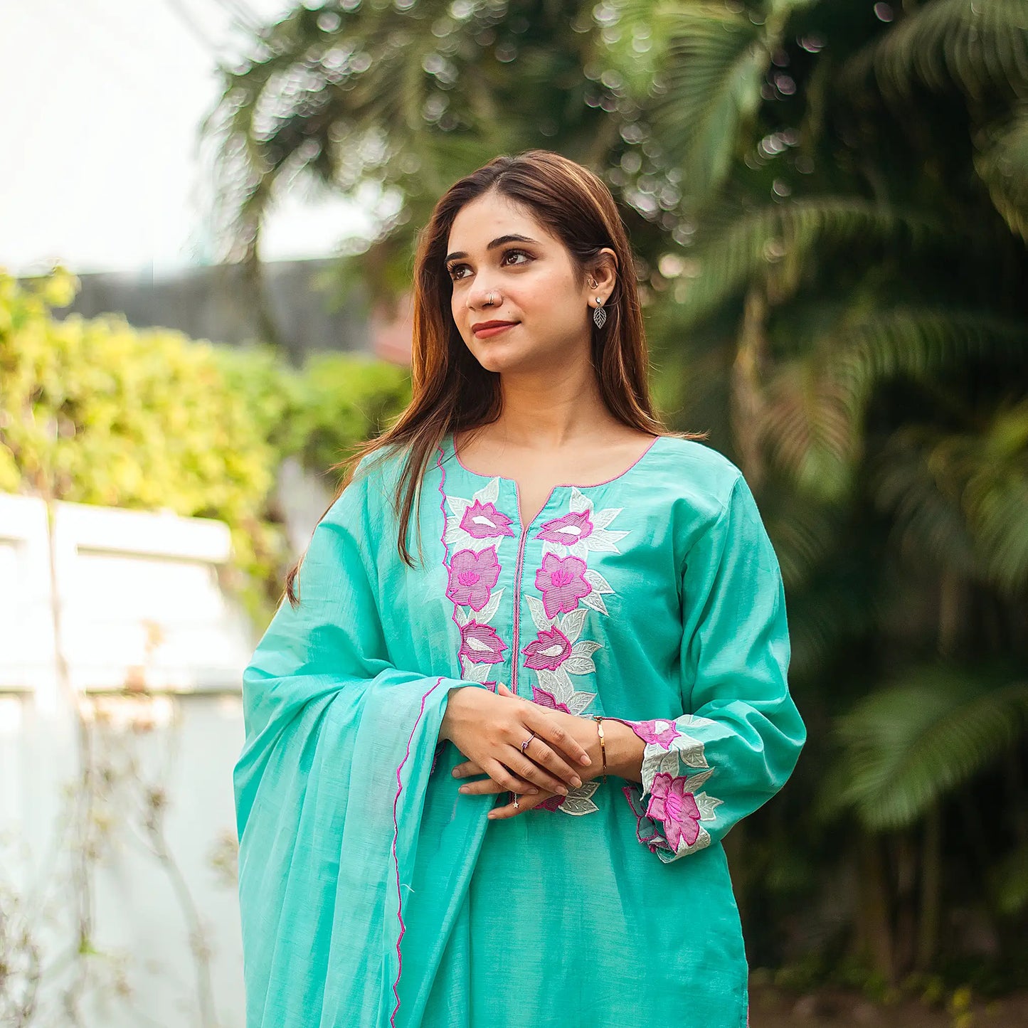 Close-up of an Indian model wearing a blue chanderi kurta and matching dupatta with purple and pink floral patchwork.