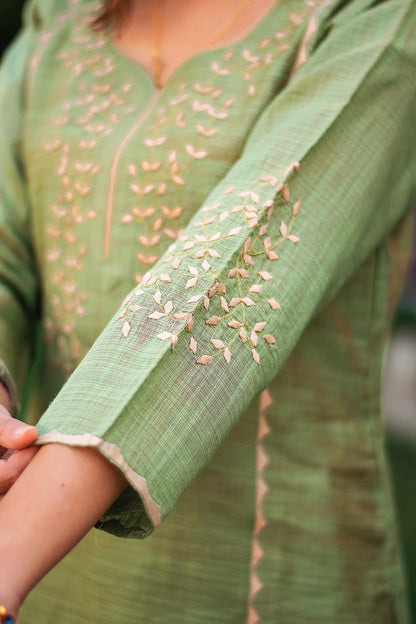 Close-up of the beige applique detailing on the sleeve of the green jute silk kurta.