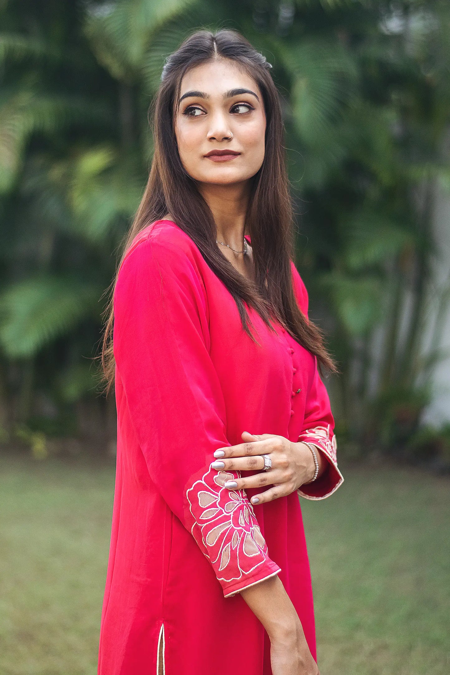 Side view of an Indian model in a red organza kurta, highlighting the intricate gold cutwork on the sleeve cuff.