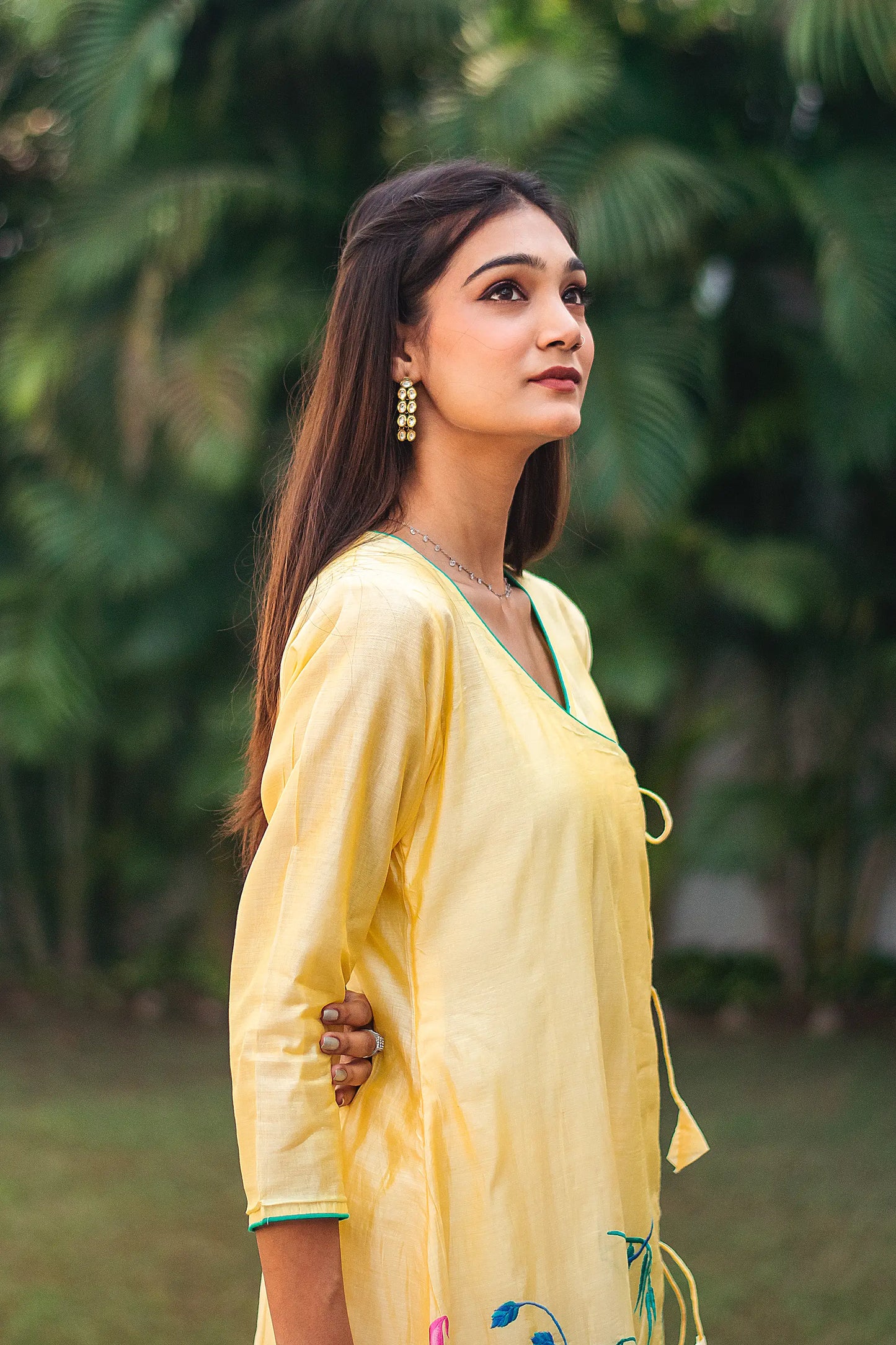 Indian woman posing sideways in a yellow chanderi angrakha.