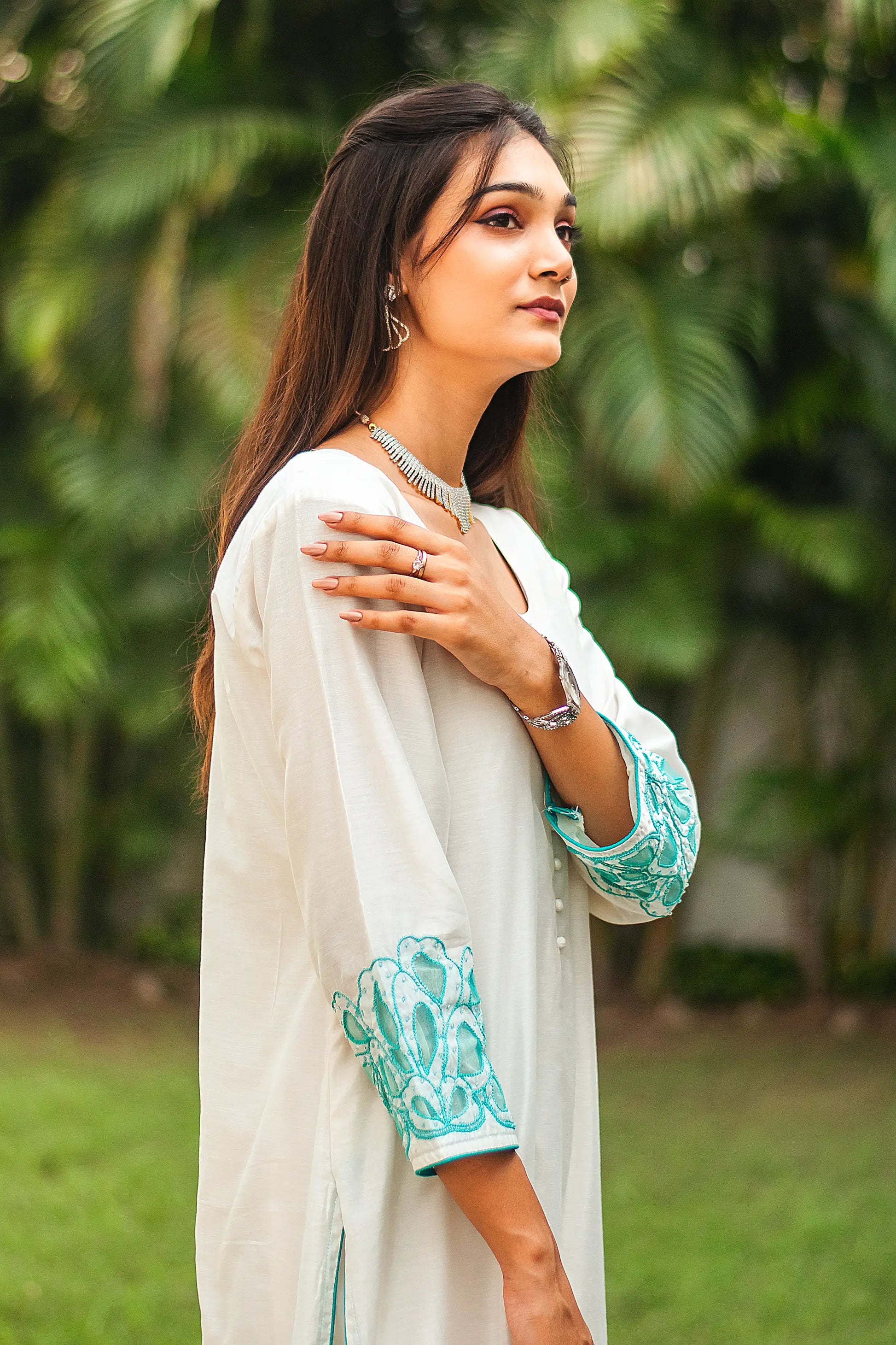 Right side upper half view of a model wearing the off-white Chanderi suit with cyan green floral cutwork, highlighting the suit's elegant silhouette