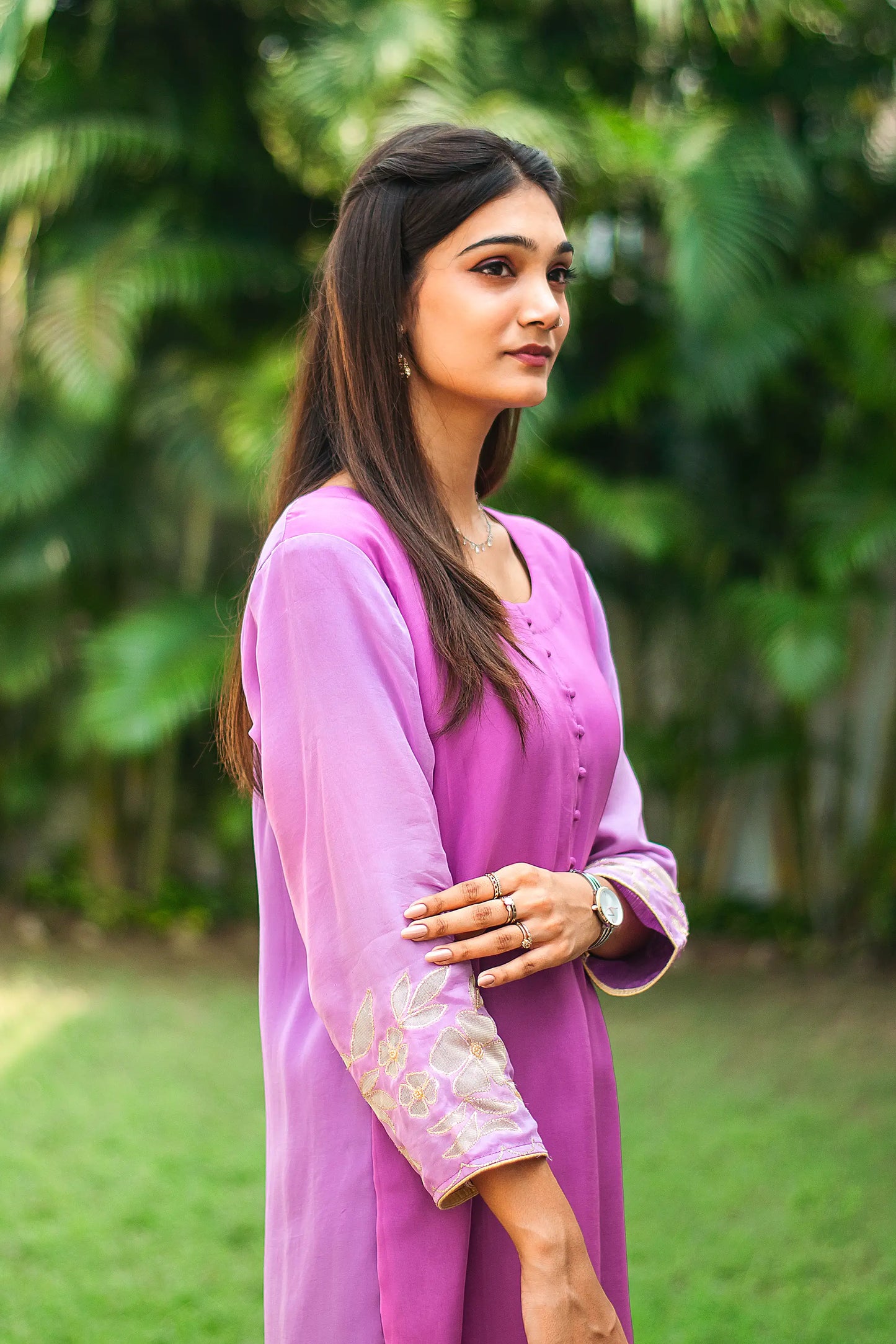 Side pose of an Indian model wearing a light purple organza kurta with golden floral cutwork around the cuffs.