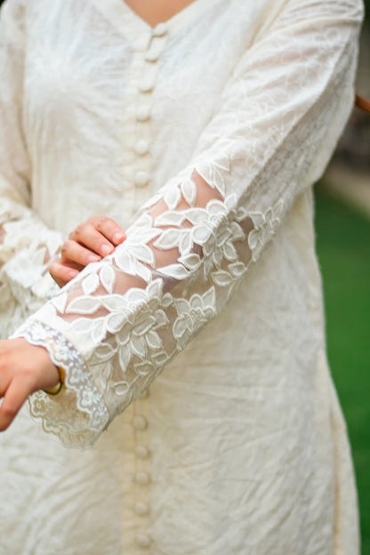 Detailed view of the floral cutwork and lace detailing on the sleeve cuff of the white cotton kurta.