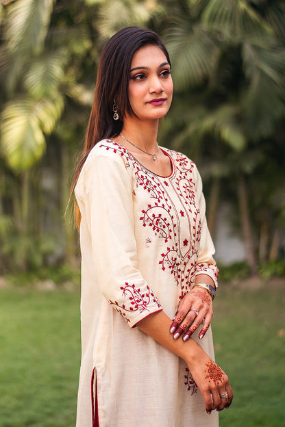  Indian model in a side pose, highlighting the straight-cut silhouette of the beige chanderi kurta with maroon applique work.