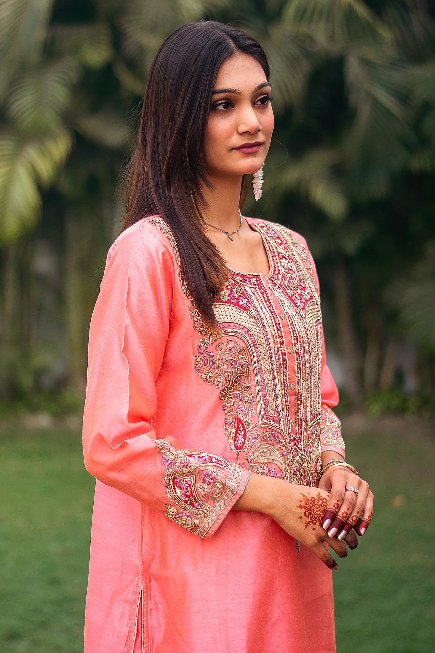 Side view of an Indian model in a peach chanderi kurta with intricate zardozi work on the yoke and cuffs.