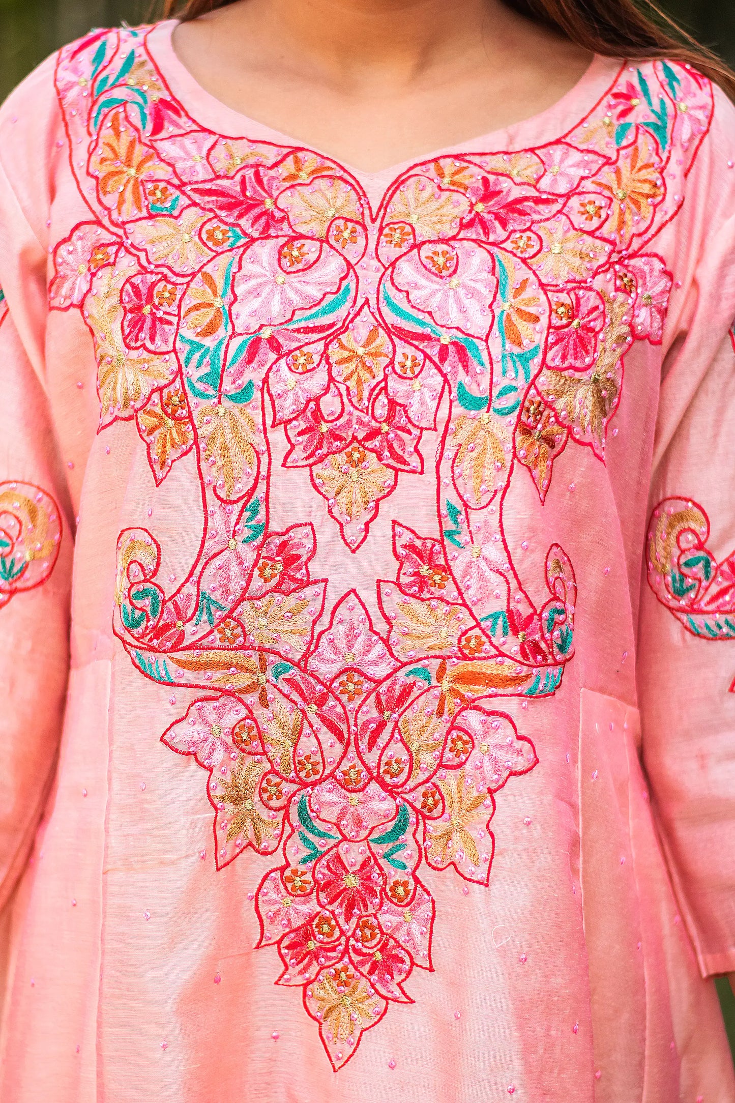 Zoomed-in view highlighting the intricate multicoloured resham embroidery on the yoke of the peach kurta.