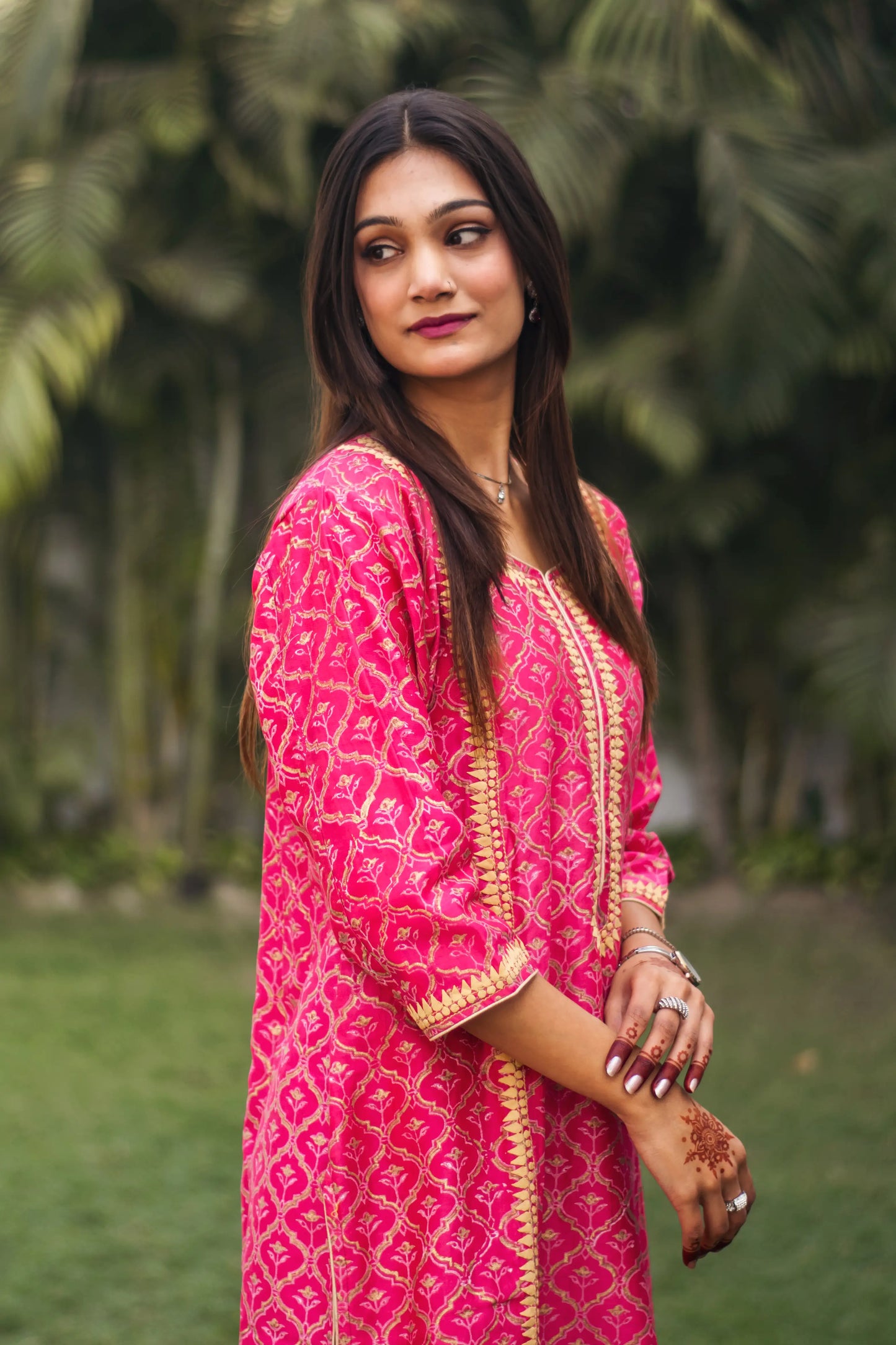 Side view of an Indian model in a magenta chanderi kurta with beige applique work along the yoke and cuffs.