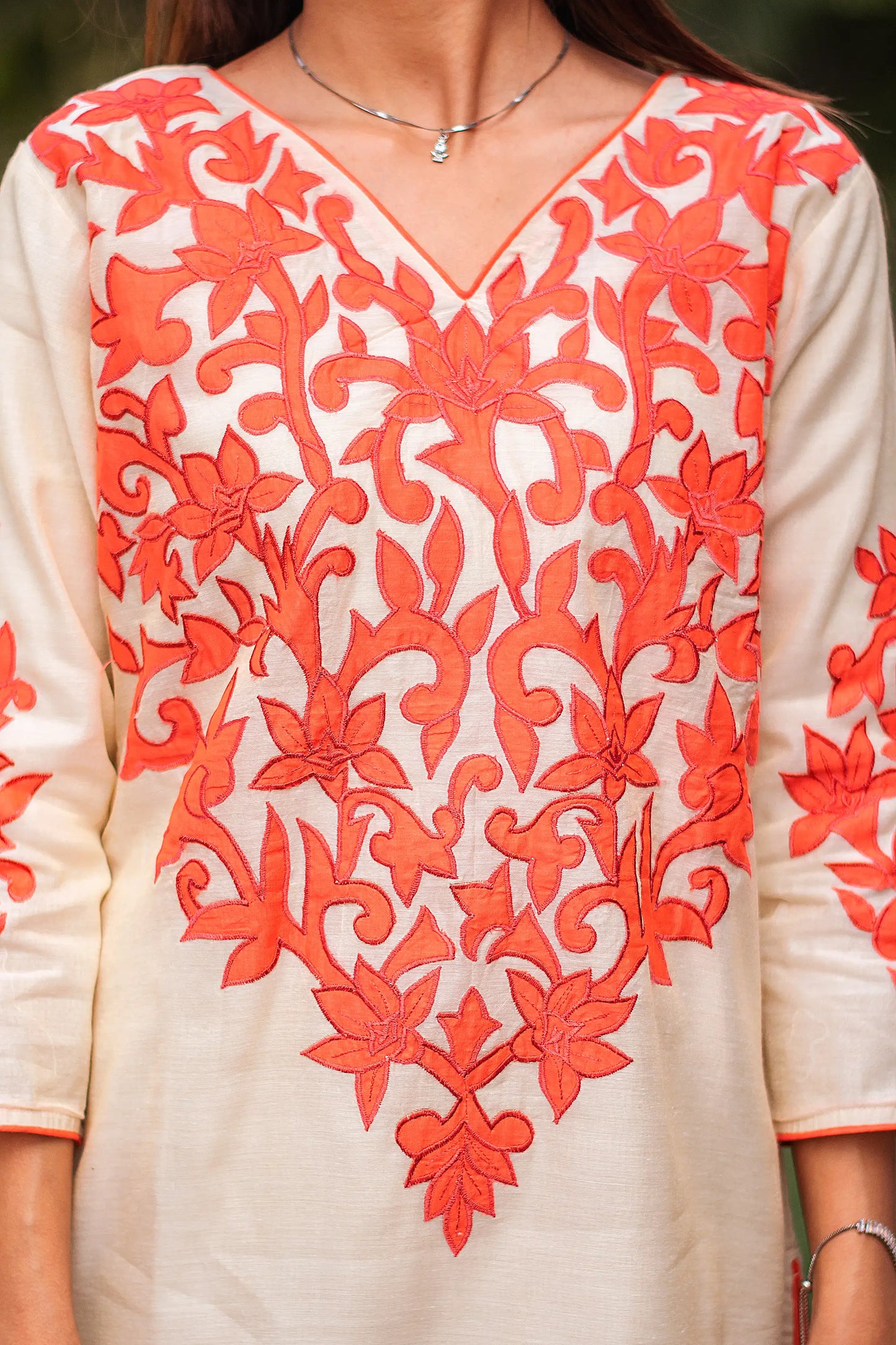 Close-up of the orange floral patchwork on the yoke of the beige chanderi kurta.