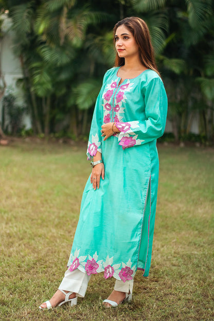 Side profile of an Indian model in a blue chanderi kurta featuring pink piping and purple patchwork, paired with off-white trousers.