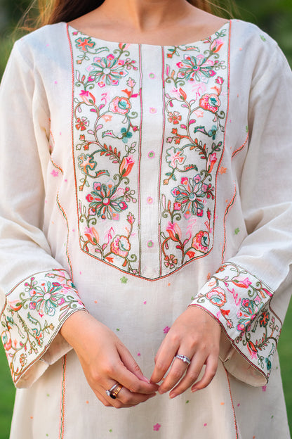 Close-up of Kashmiri floral embroidery on the yoke of the off-white kurta, with intricate peach, pink, and green thread work.