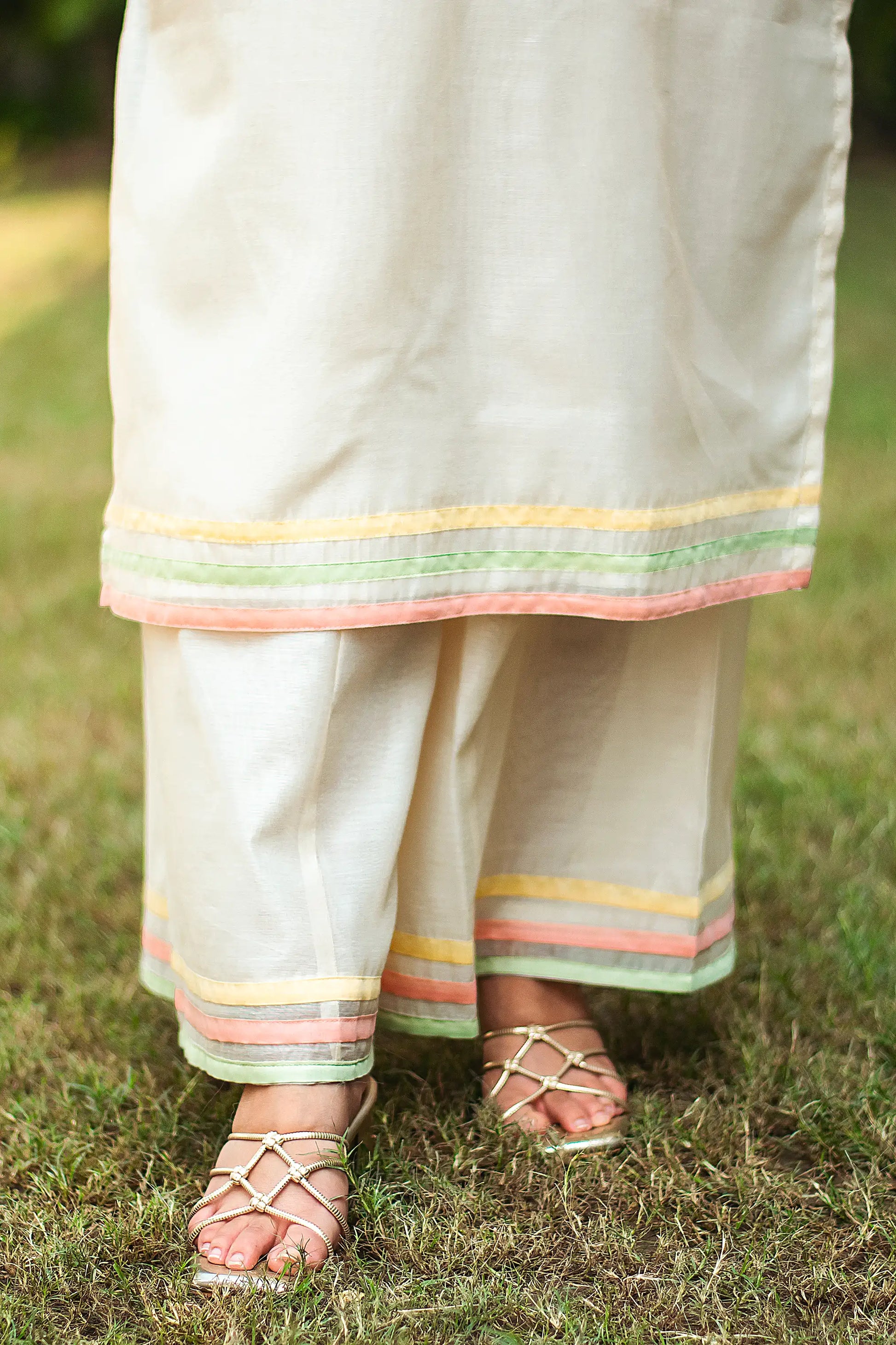 Close-up of the off-white palazzo with pastel piping, worn by the Indian model.