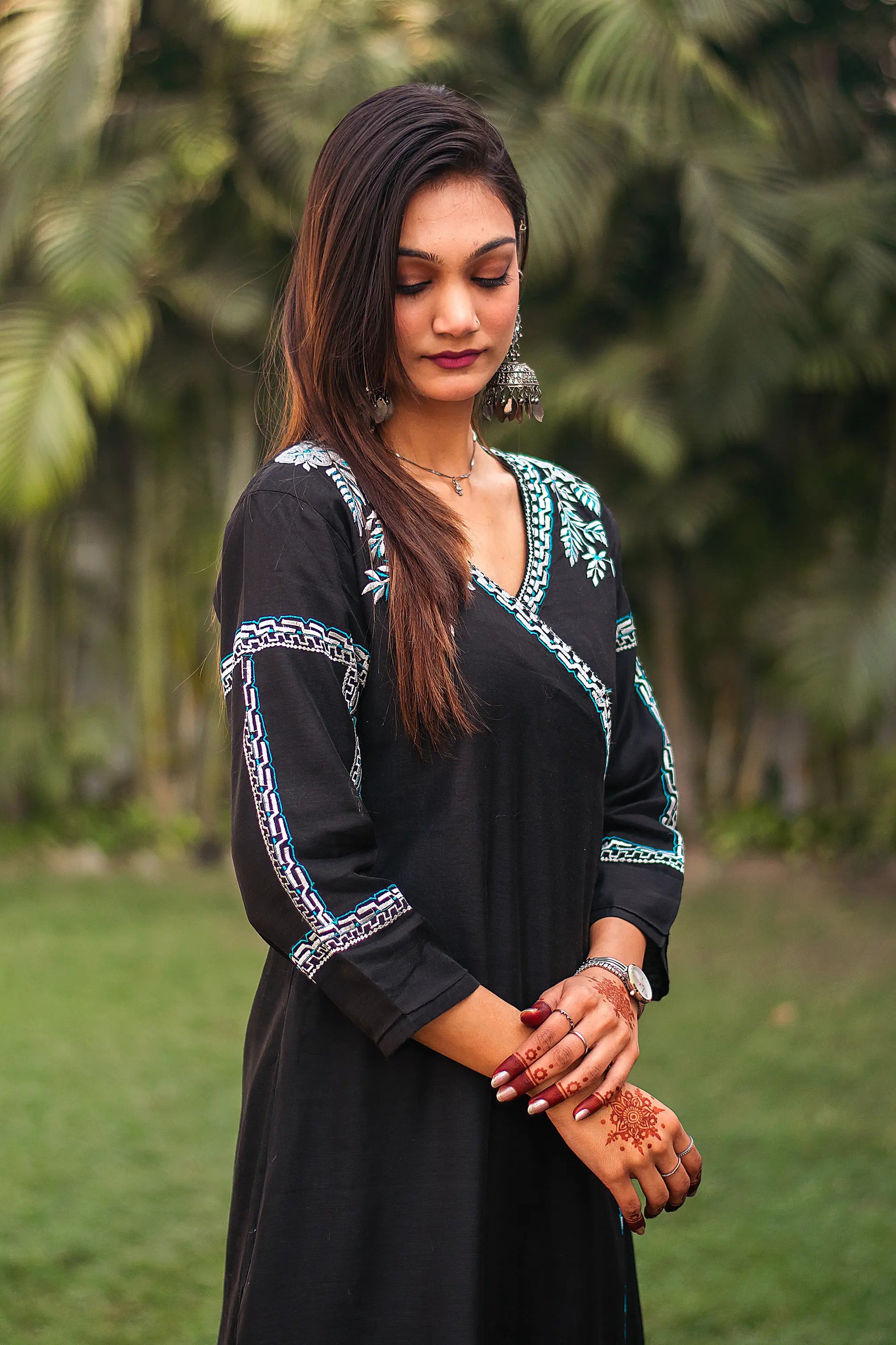 Indian model poses sideways, highlighting the black chanderi angrakha kurta with white and blue embroidery.