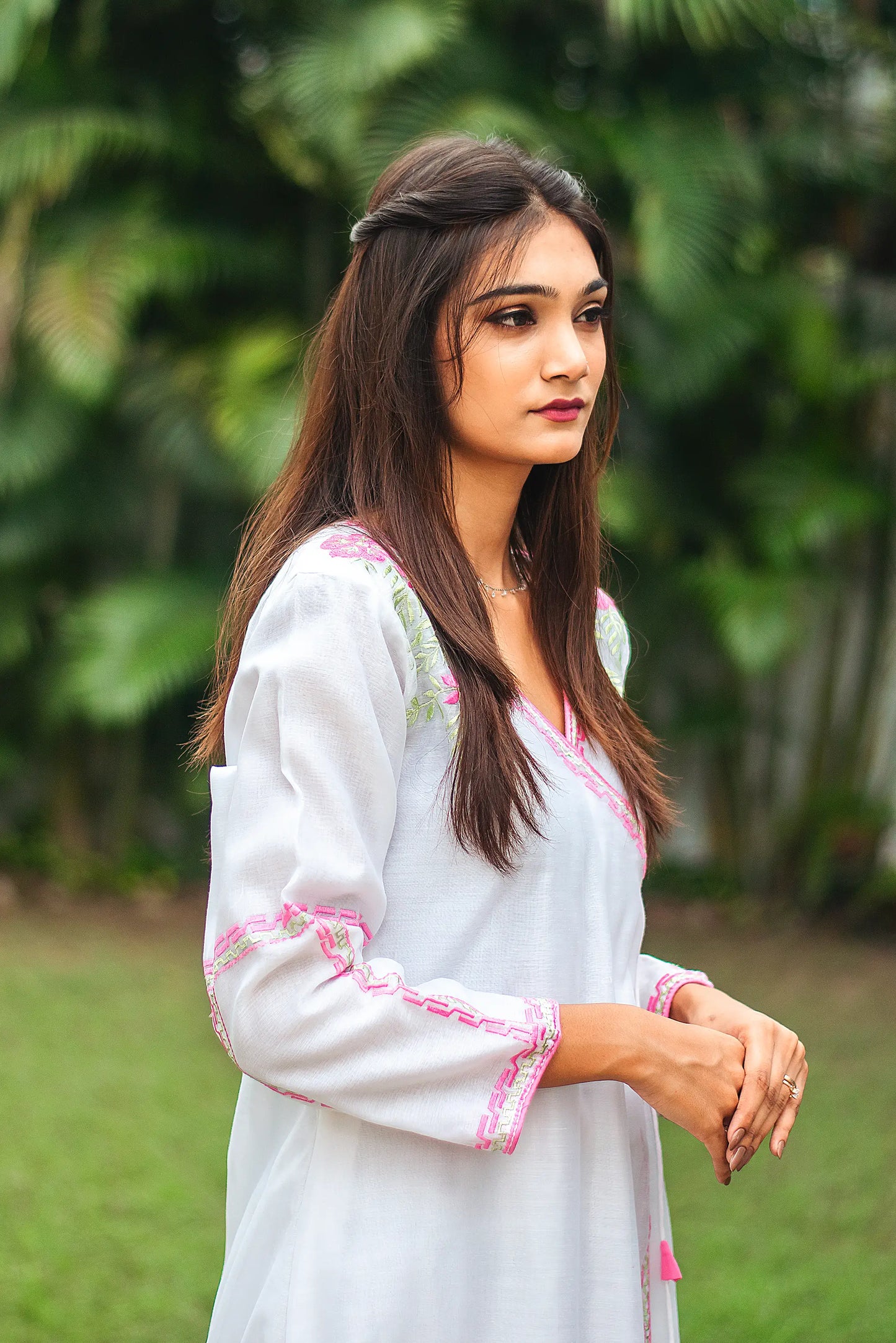 ide profile of an Indian model wearing a white chanderi angrakha kurta with pink and green geometric embroidery