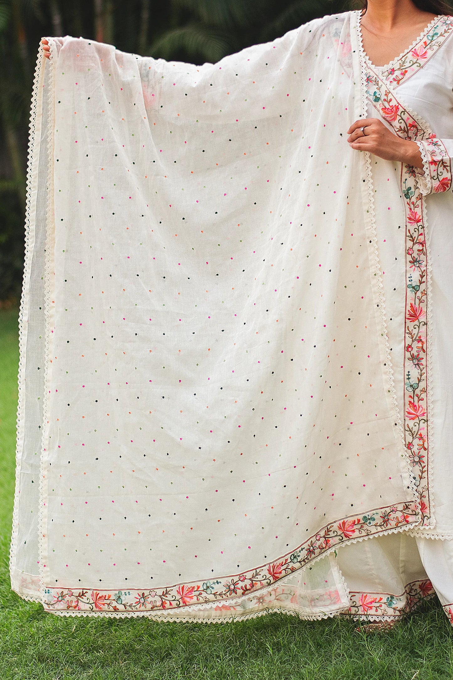 An Indian woman gracefully draping a delicate, off-white cotton dupatta over her shoulder, complementing her matching angarkha