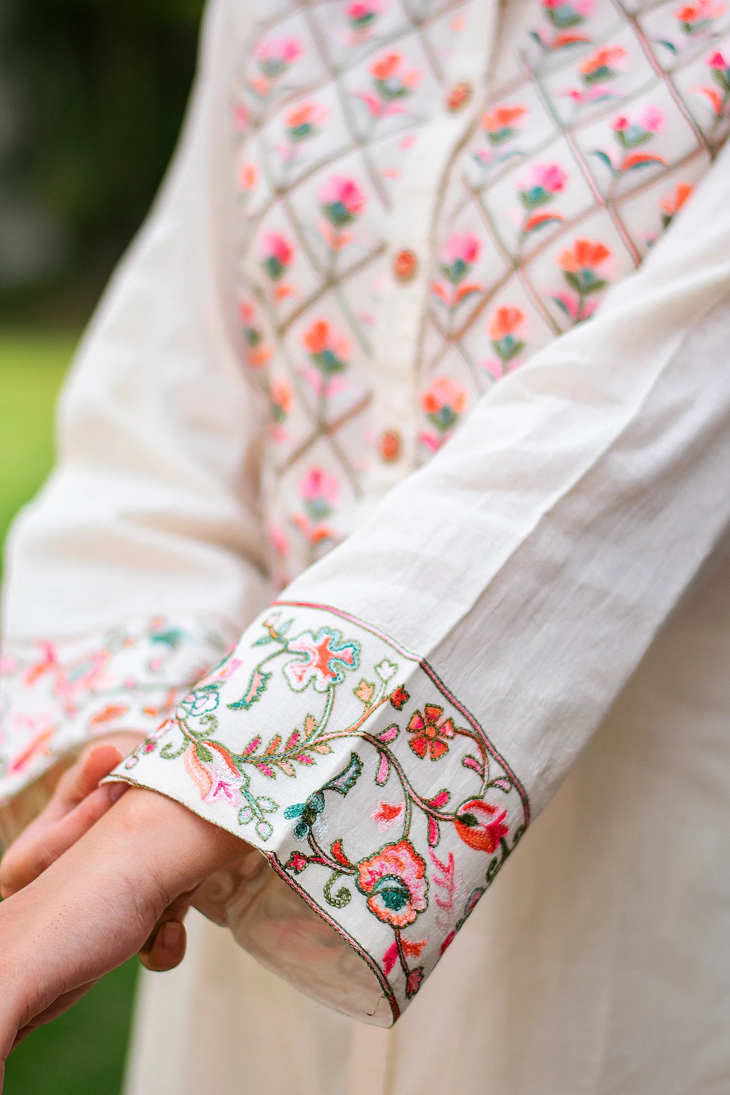 Close-up of Kashmiri embroidery on the sleeve of an off-white cotton kurti, highlighting floral thread work.