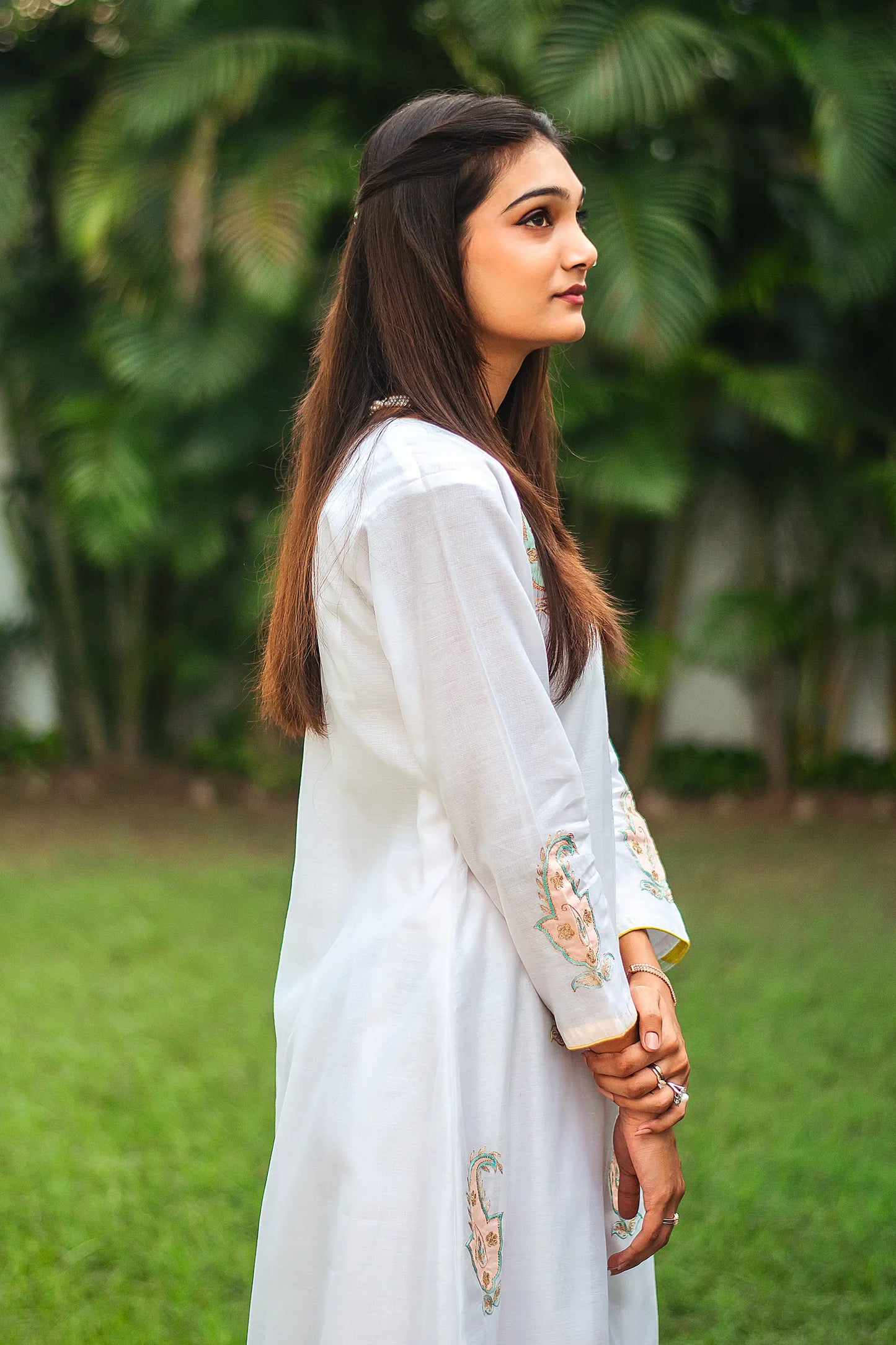  Side profile of an Indian model in a white chanderi angarkha kurta featuring intricate kairi (paisley) patchwork.