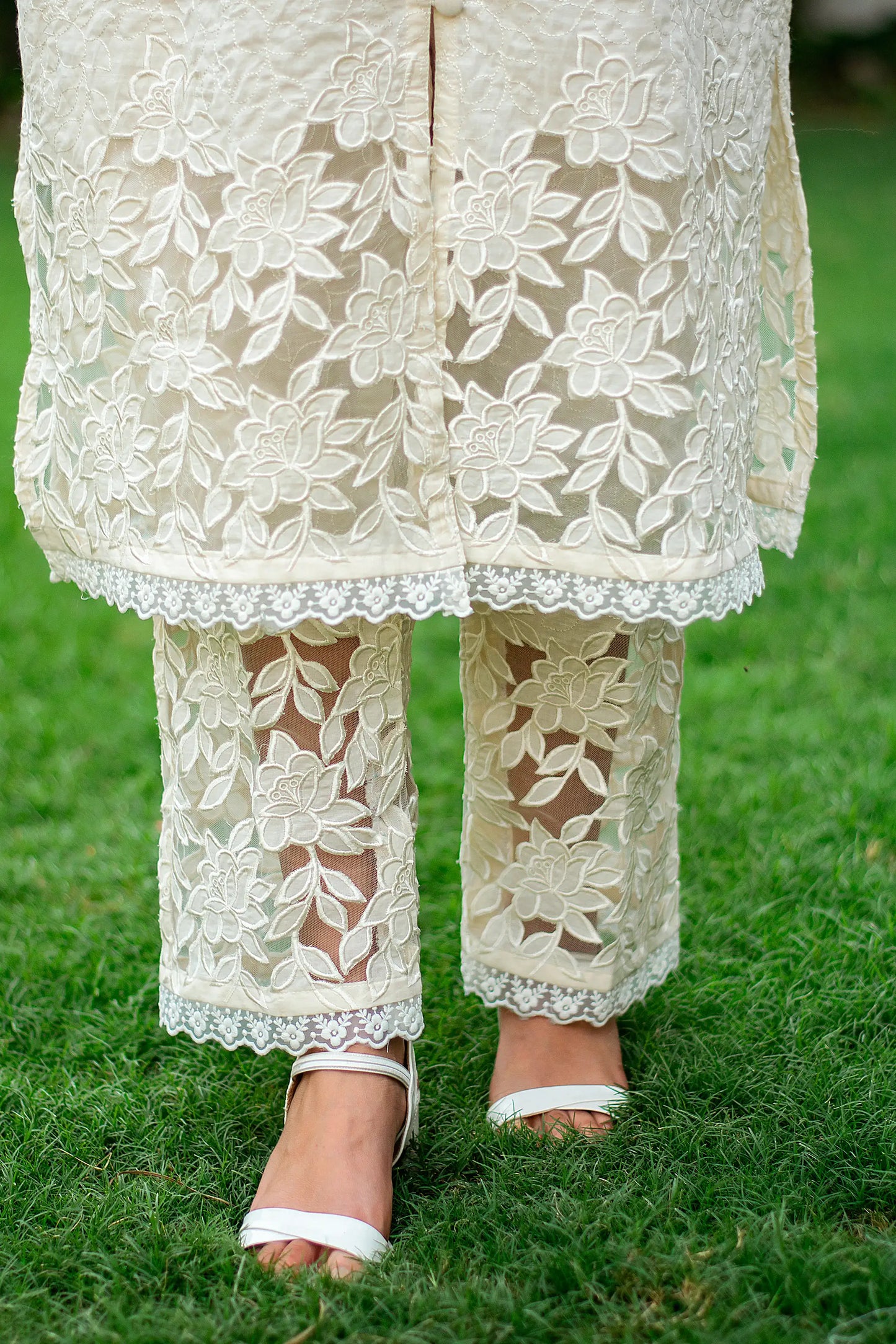 Close-up of an Indian model in plain white trousers, part of the cutwork-embroidered kurta set.