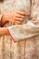 An indian woman wearing a printed staple tussar gold A line kurta. The A line kurta has double kali in red colour. The woman's left side is facing the camera and the camera has zoomed in to focus on the print of the kurta.