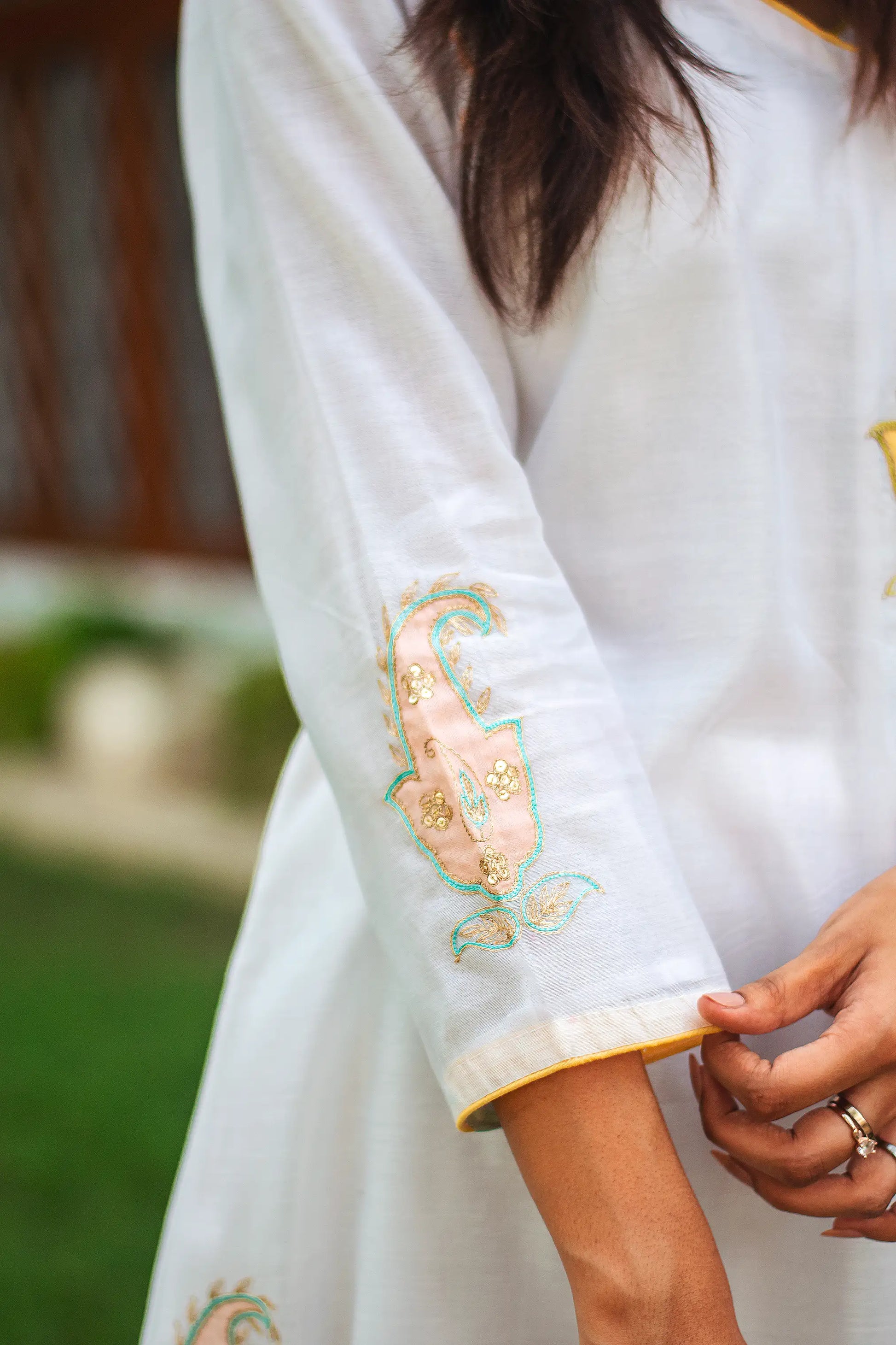 Zoomed-in view of the kairi (paisley) patchwork on the sleeve of a white chanderi angarkha kurta.