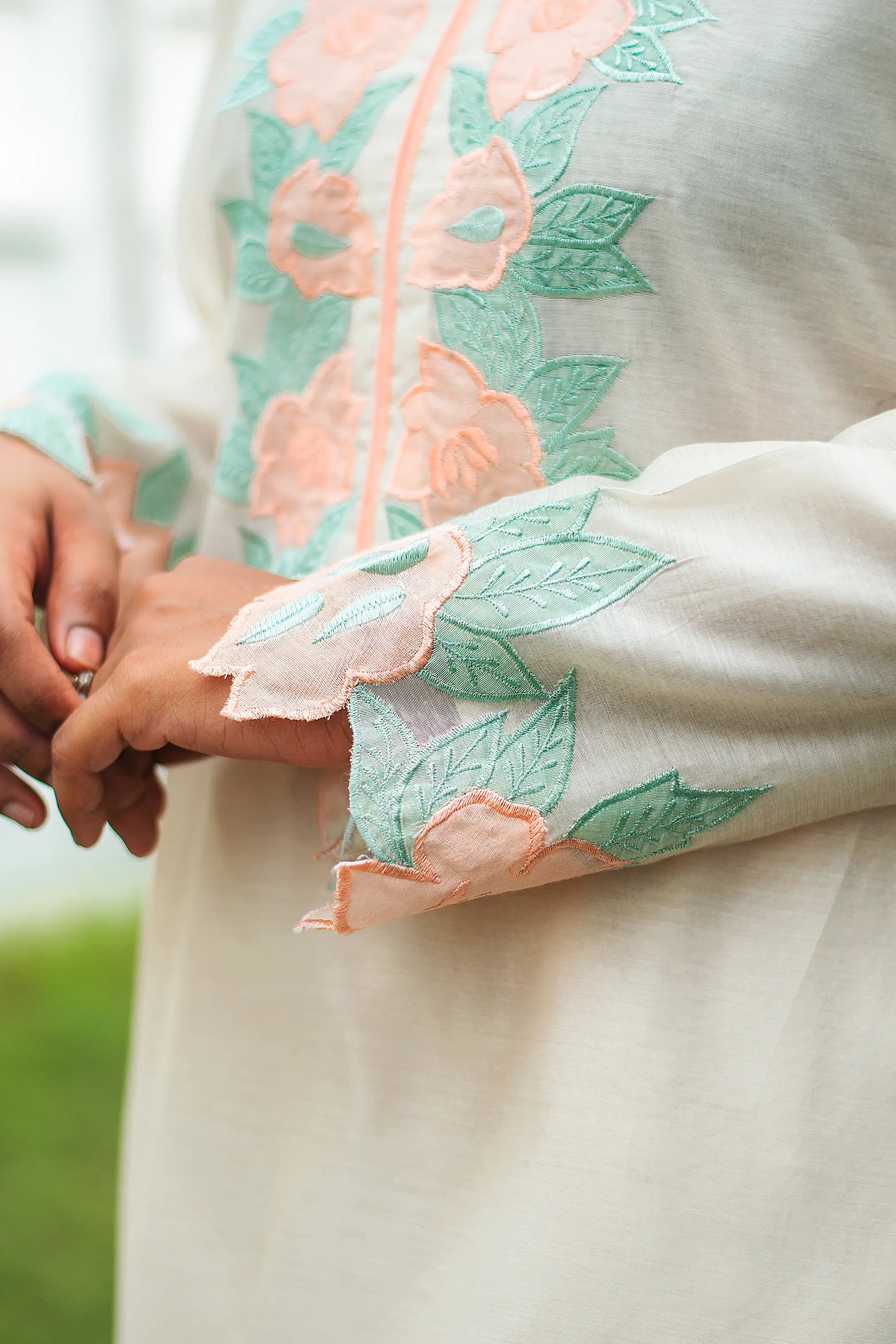 Close-up of peach floral patchwork on the sleeve of a cream chanderi kurta.