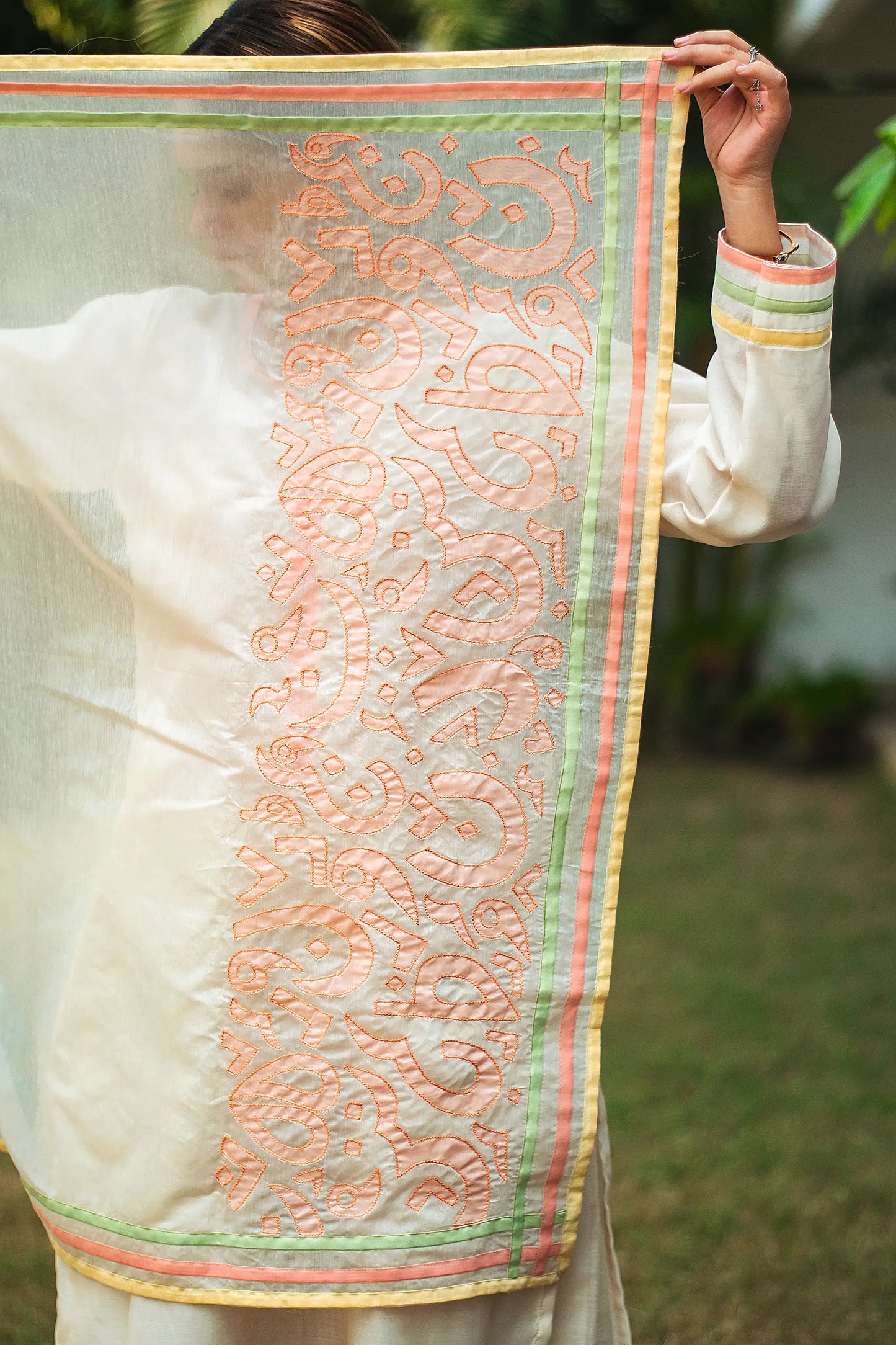 Indian model displaying an off-white chanderi dupatta featuring pastel-colored patchwork motifs and piping.