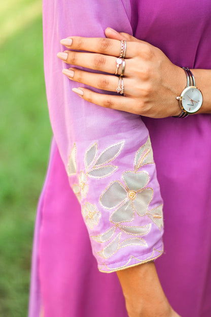 Zoomed-in view of golden floral cutwork on the sleeve cuff of a light purple organza kurta.