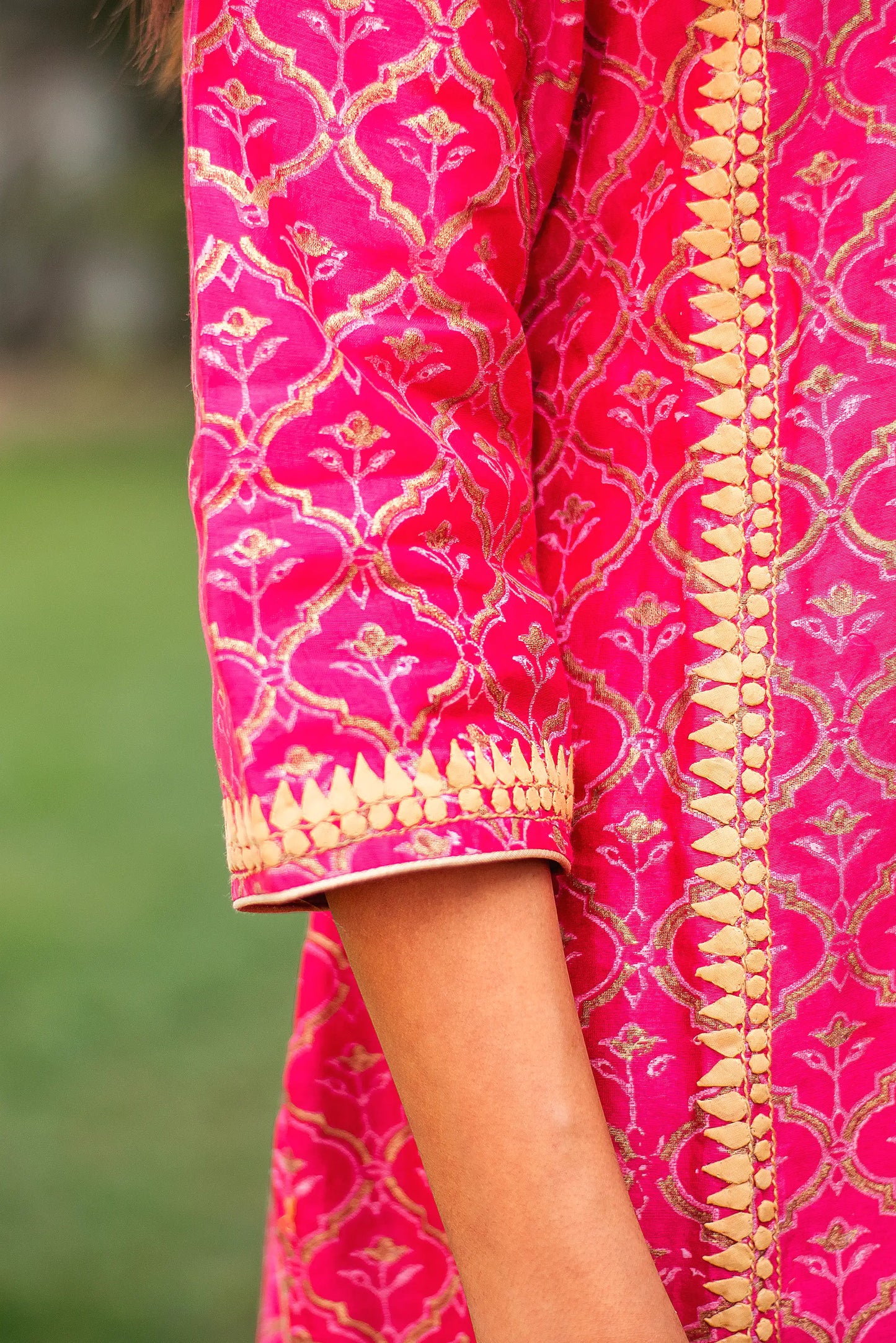 Close-up of the beige applique detailing on the sleeve cuff of the magenta chanderi kurta.