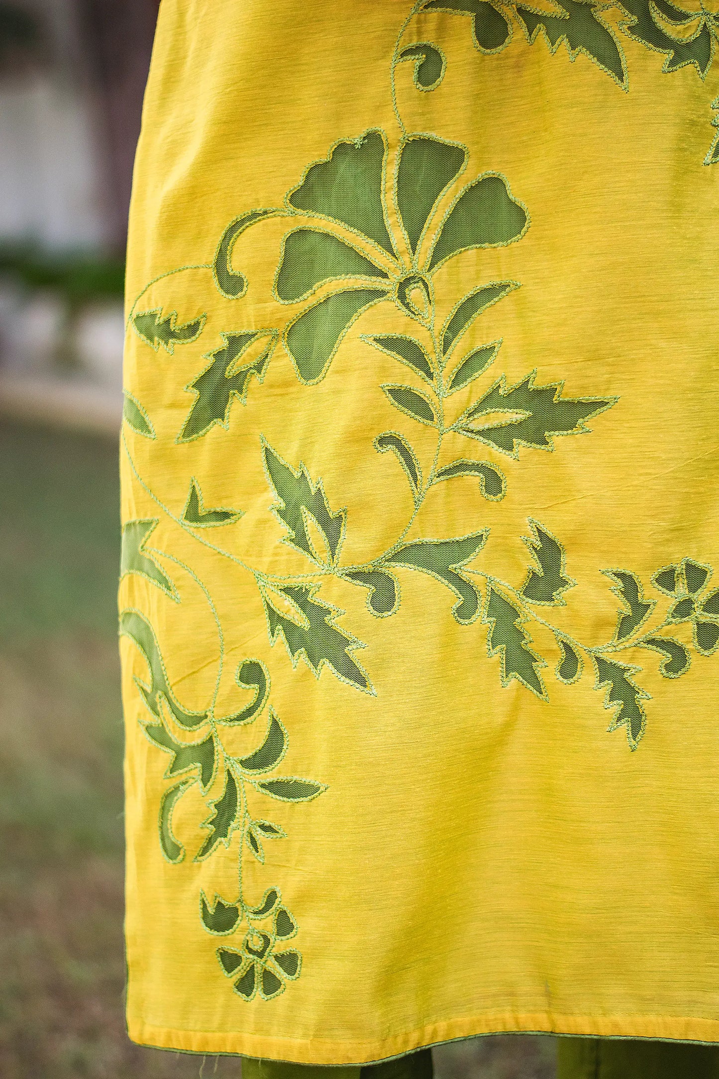 Detailed shot of the dark green cutwork floral vine design on the kurta as styled by the model