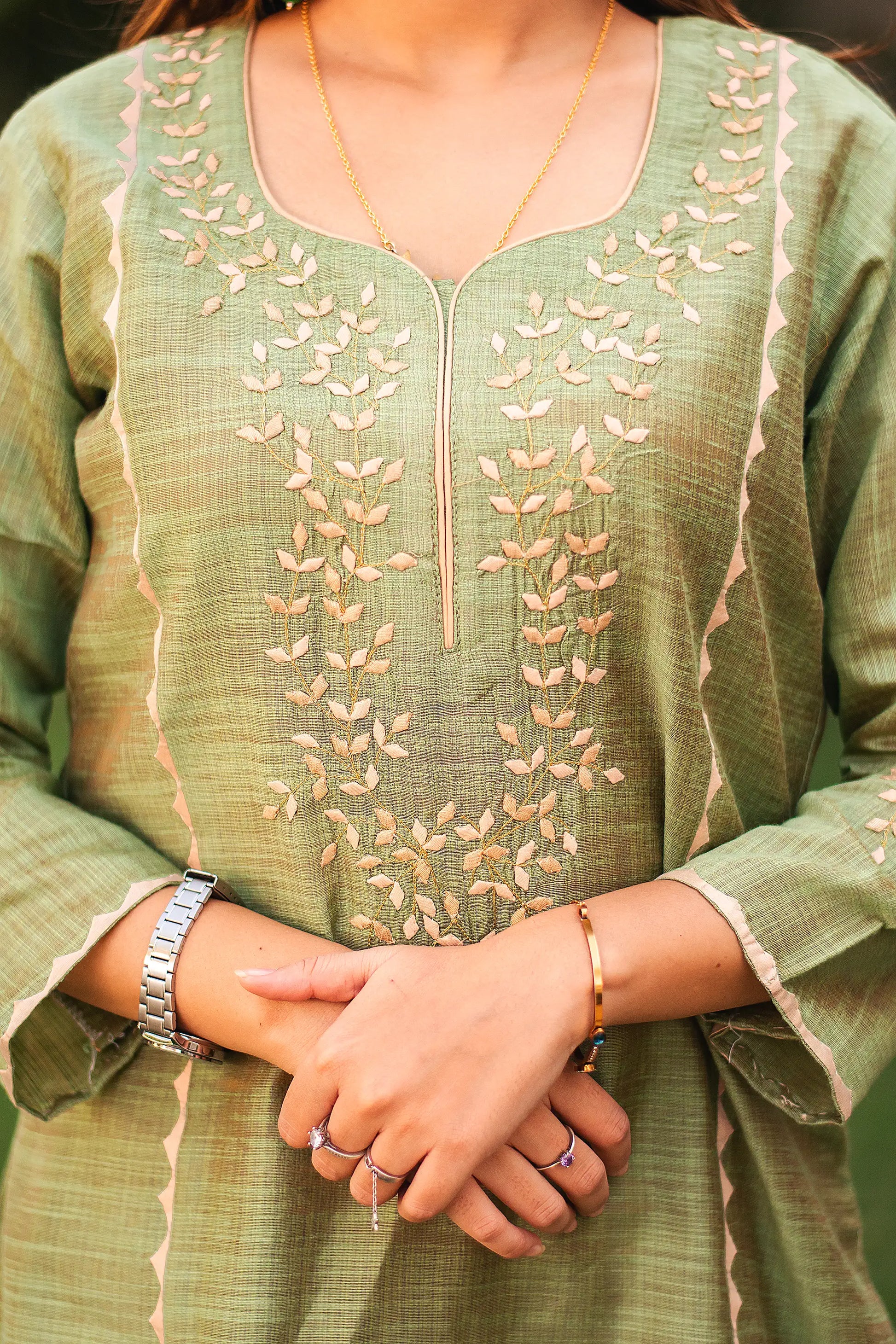 Close-up of the intricate beige applique work on the yoke of the green jute silk kurta.