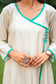 Close-up of the beige chanderi fabric and the neckline, buttons and the green piping on the angrakha