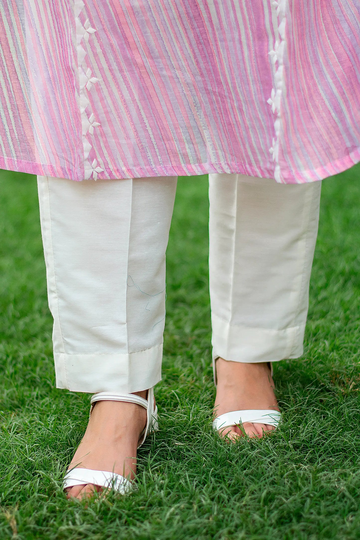 Close-up of an Indian model in plain off-white cotton trousers, part of the light pink kurta set.