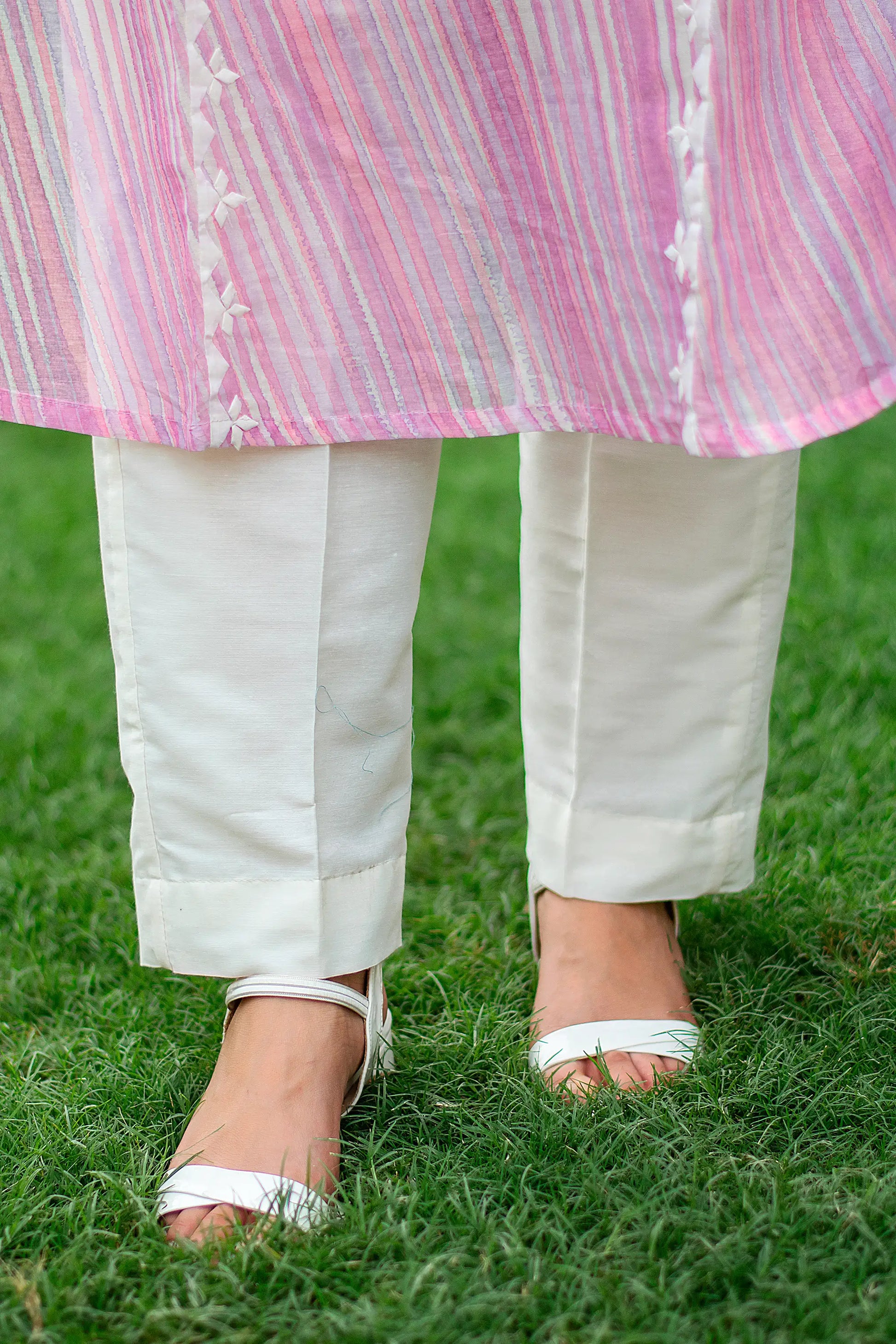 Close-up of an Indian model in plain off-white cotton trousers, part of the light pink kurta set.