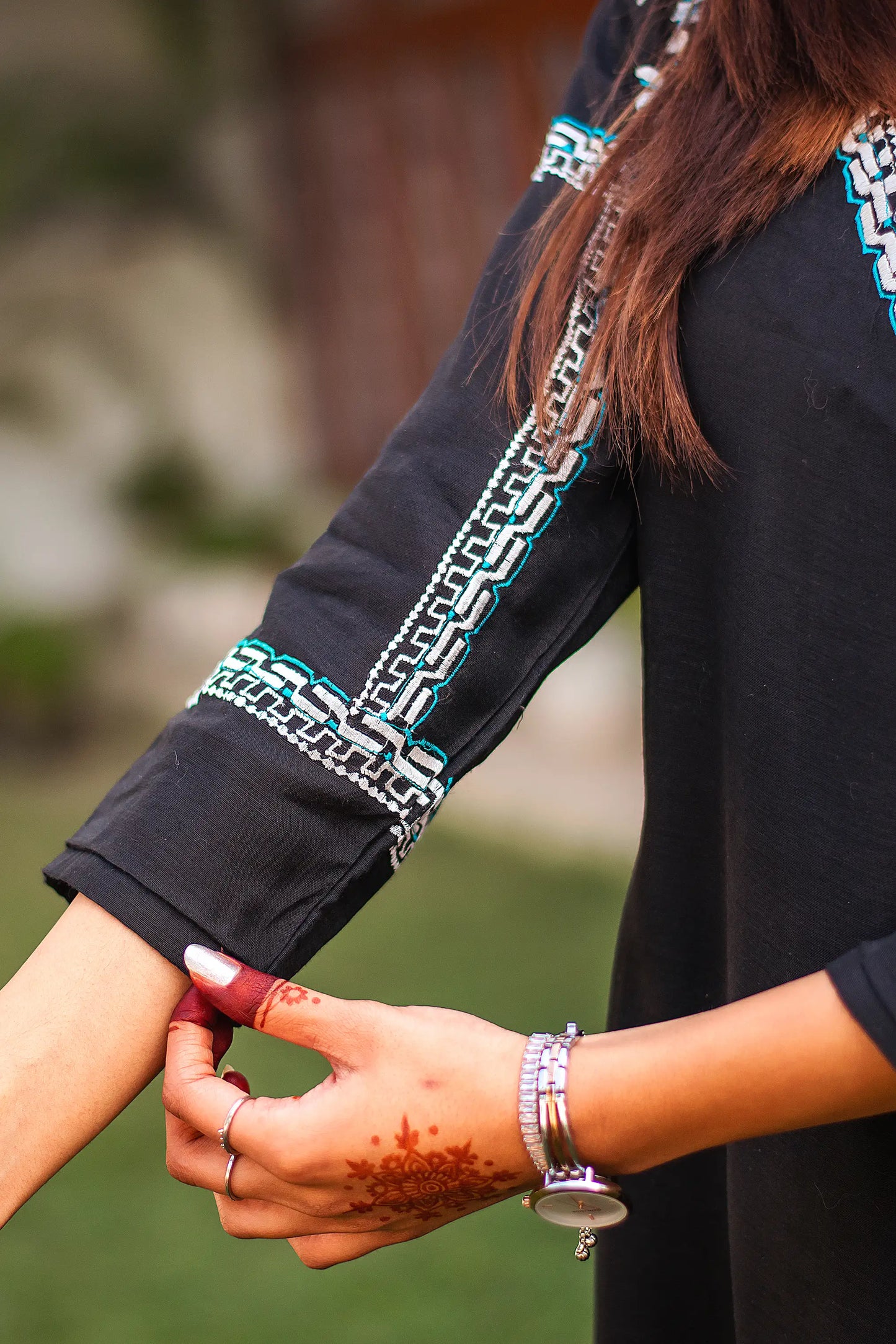 Close-up of the white geometric embroidery on the sleeve cuff of the black chanderi angrakha kurta.