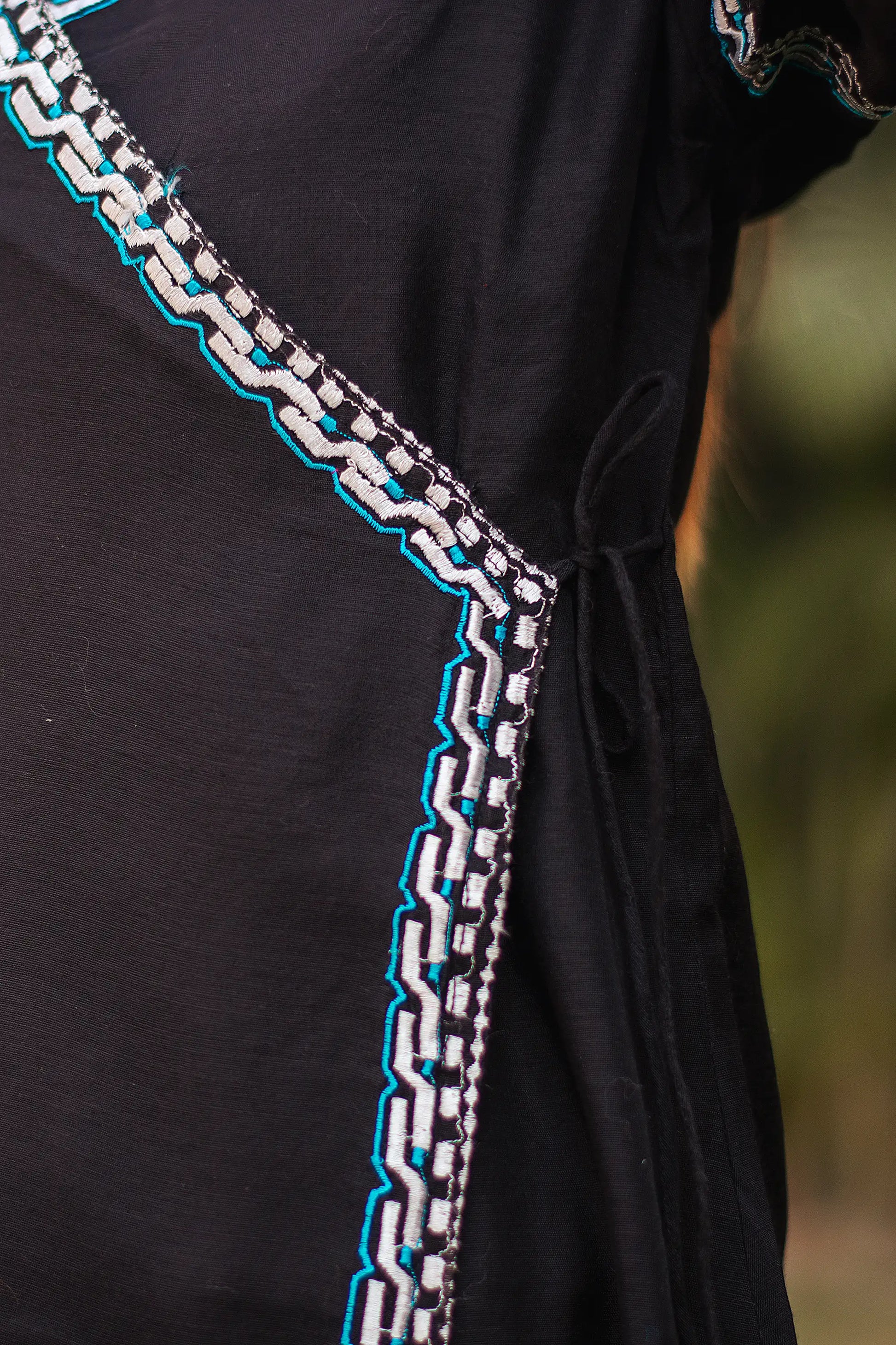 Close-up of the white and blue geometric embroidery on black chanderi angrakha kurta.