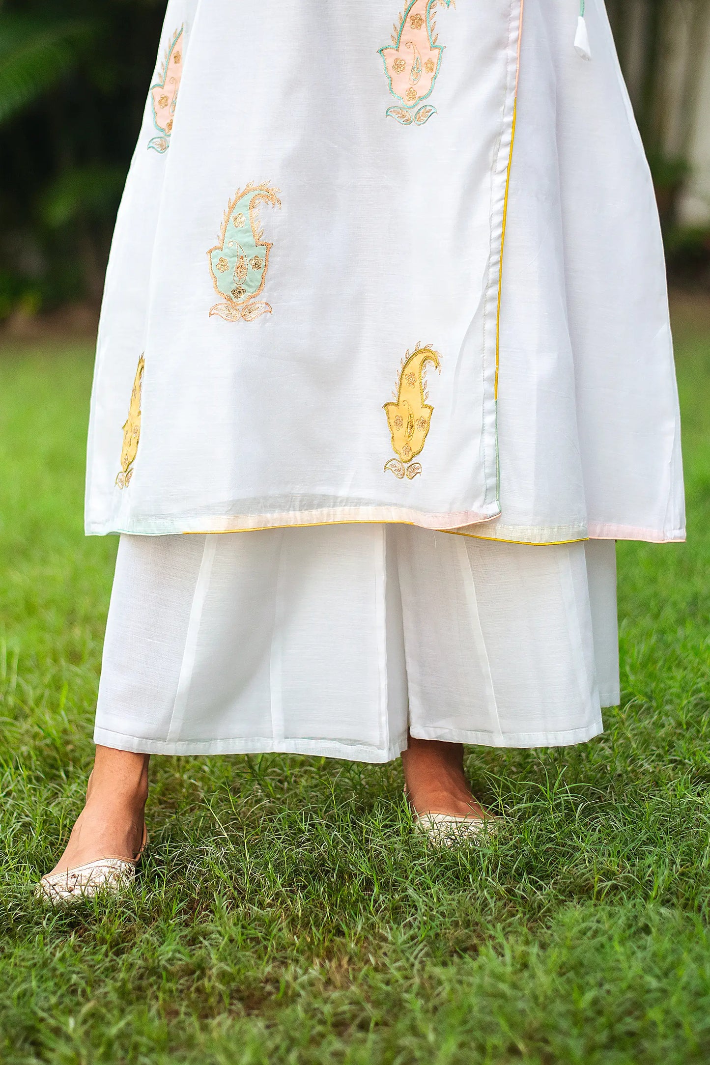 Close-up of an Indian model wearing white chanderi palazzo, part of the angarkha kurta set with kairi patchwork.