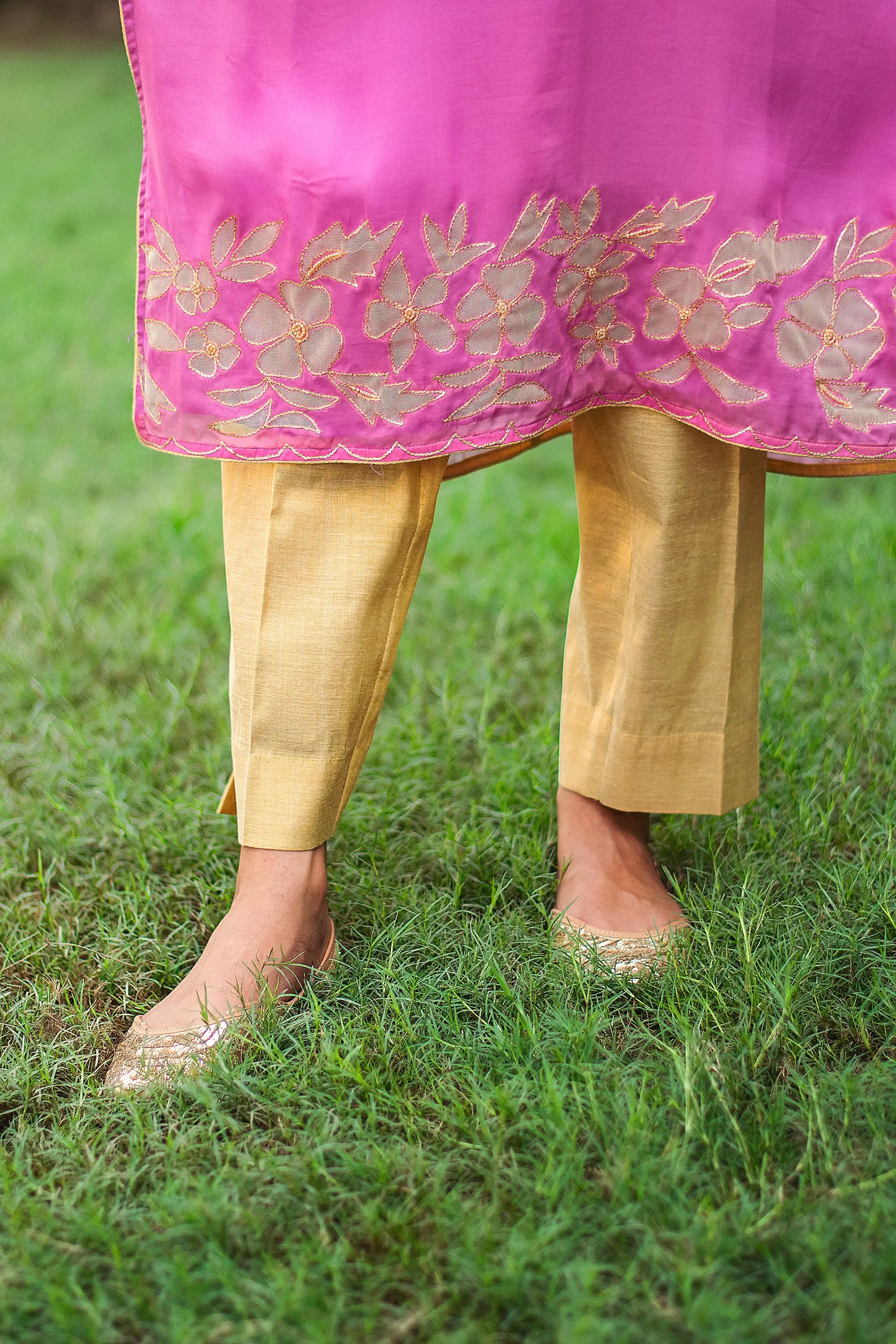 Close-up of an Indian model wearing gold trousers, part of a light purple organza kurta set with cutwork.