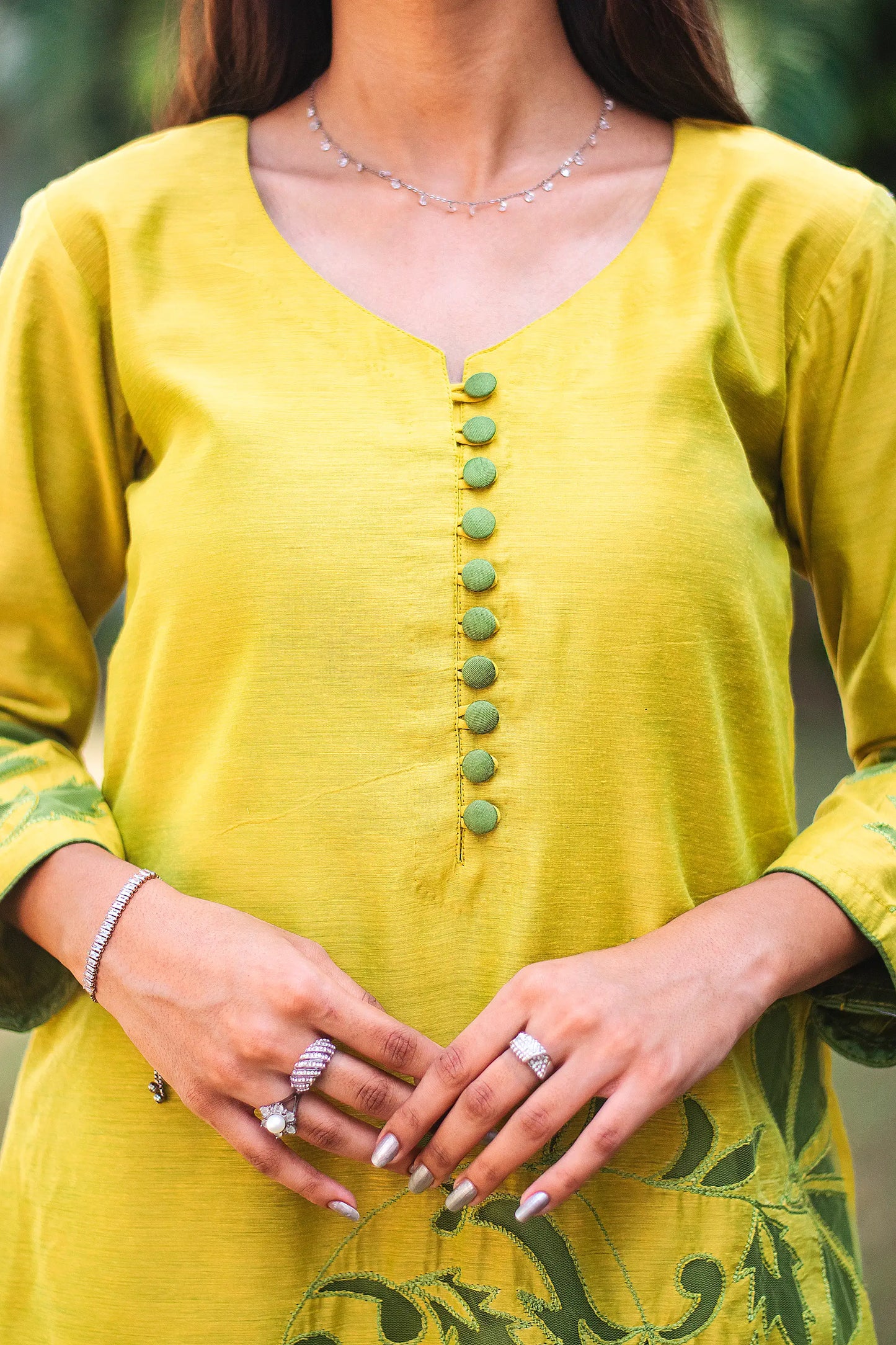 Close-up of the yellowish-green chanderi fabric and intricate green floral cutwork on the kurta on the upper half, as worn by the model