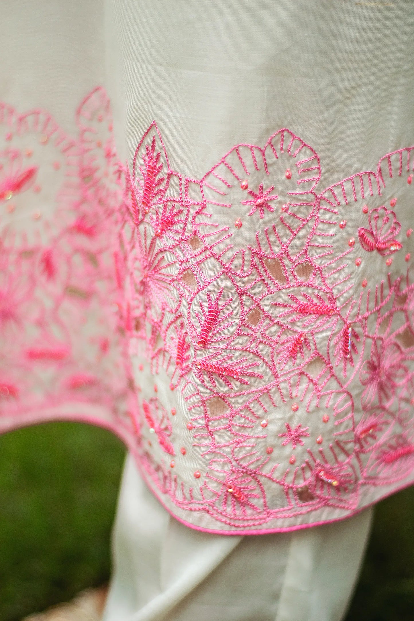 Close-up of the off-white chanderi kurta displaying detailed pink floral cutwork and sequins on the hem.