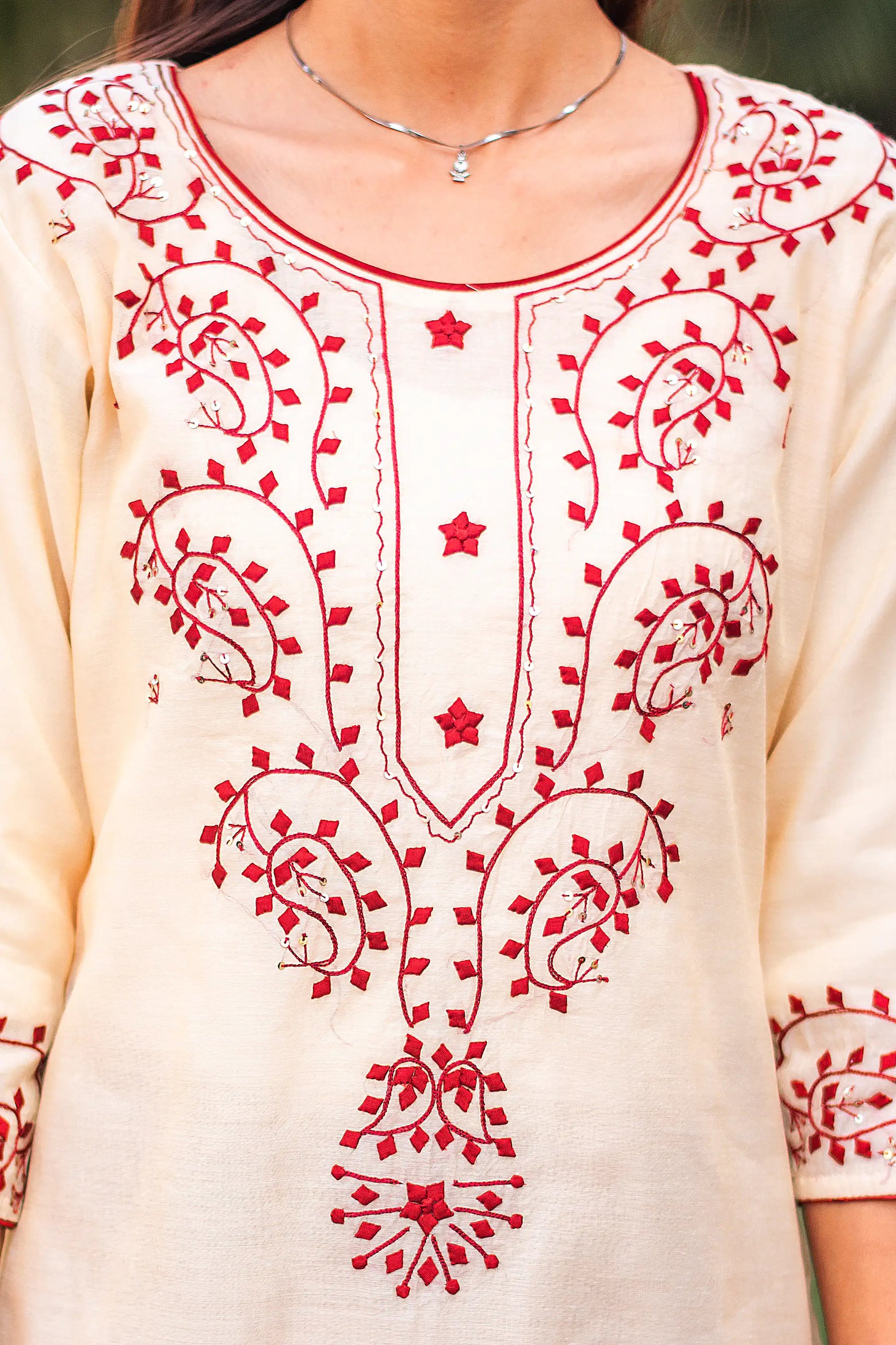 Close-up of the maroon applique paisley and geometric motifs on the yoke of the beige chanderi kurta.