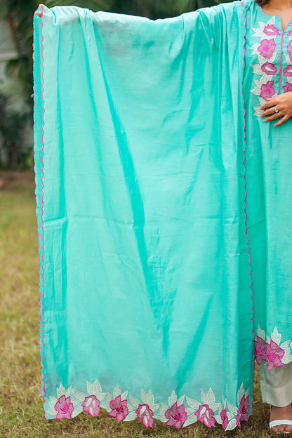 Indian model holding a blue chanderi dupatta with pink floral patchwork along two borders and pink scallop details on the other two.