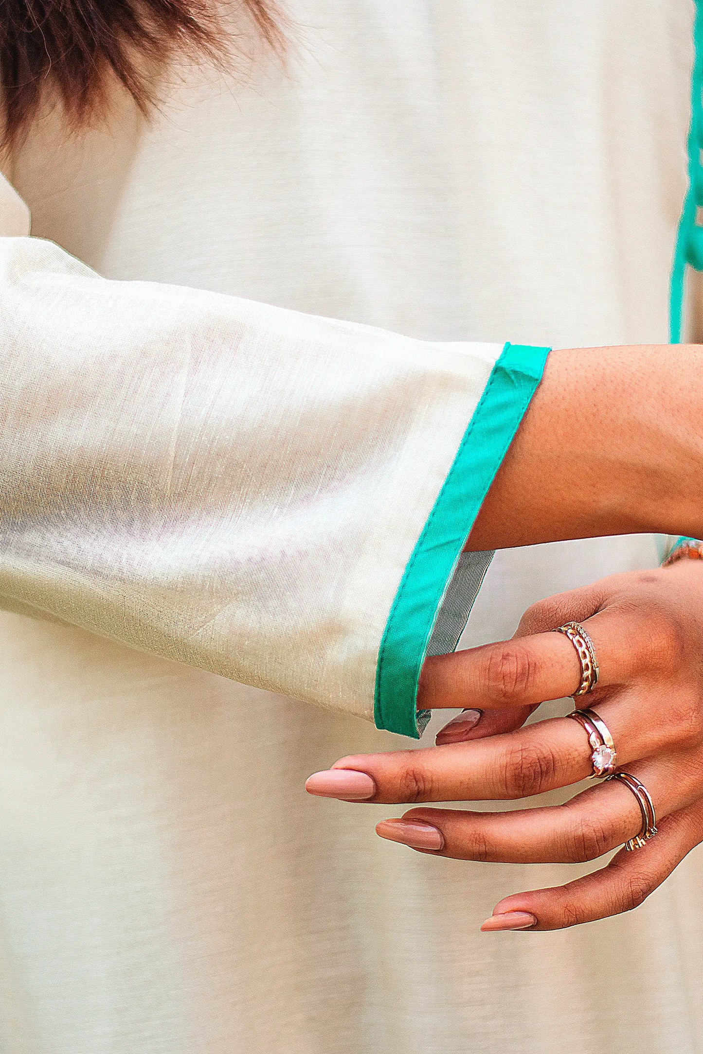 Close-up of the three-quarter sleeves of the beige angrakha, showcasing the green piping around the cuffs