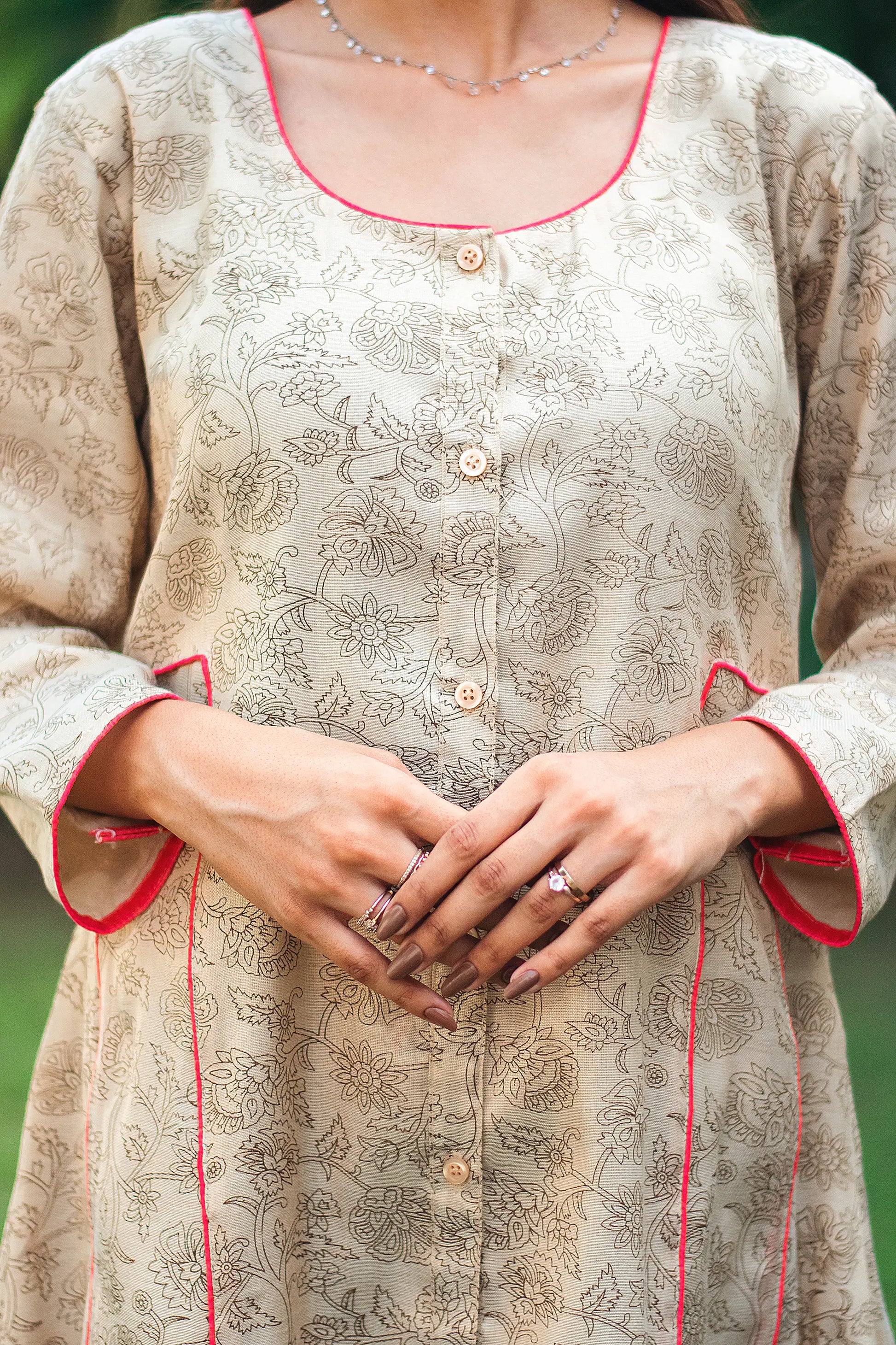 An indian woman wearing a printed staple tussar gold A line kurta. The A line kurta has double kali in red colour. The woman's left side is facing the camera and the camera has zoomed in to focus on the print of the kurta.