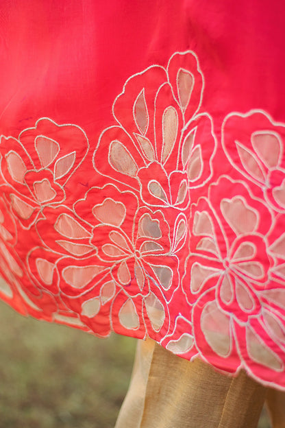 Close-up of gold floral cutwork along the hem of a red organza kurta.