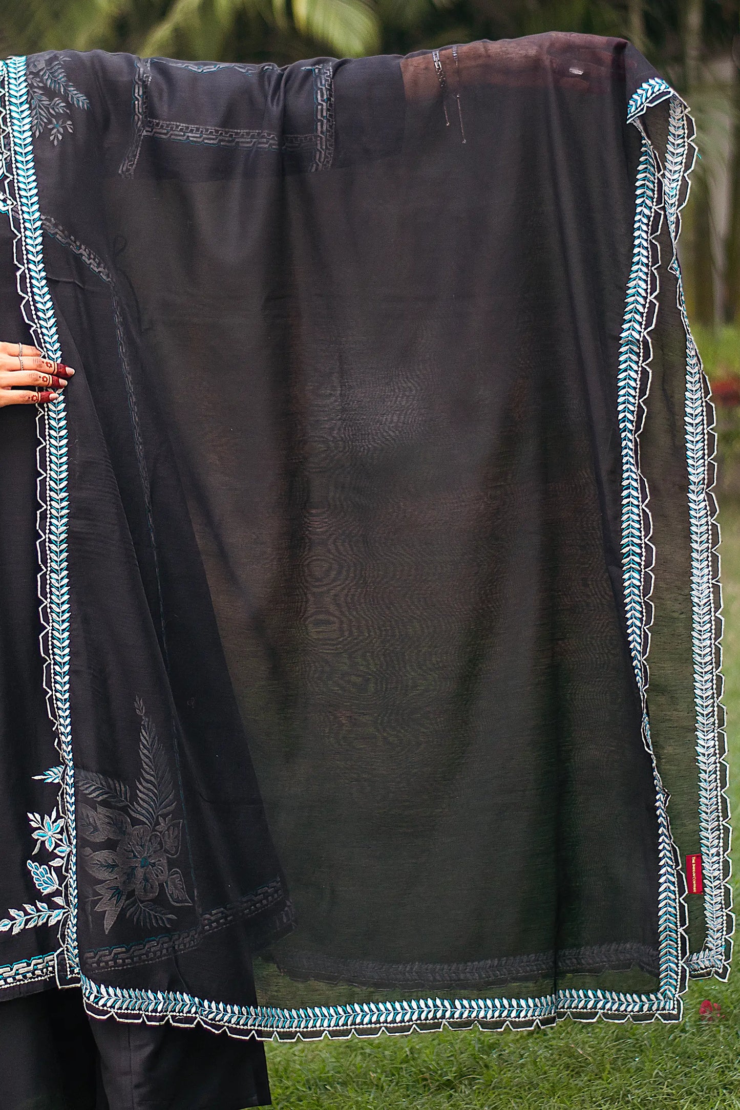 Indian model holding a black chanderi dupatta with white geometric embroidery along the borders.