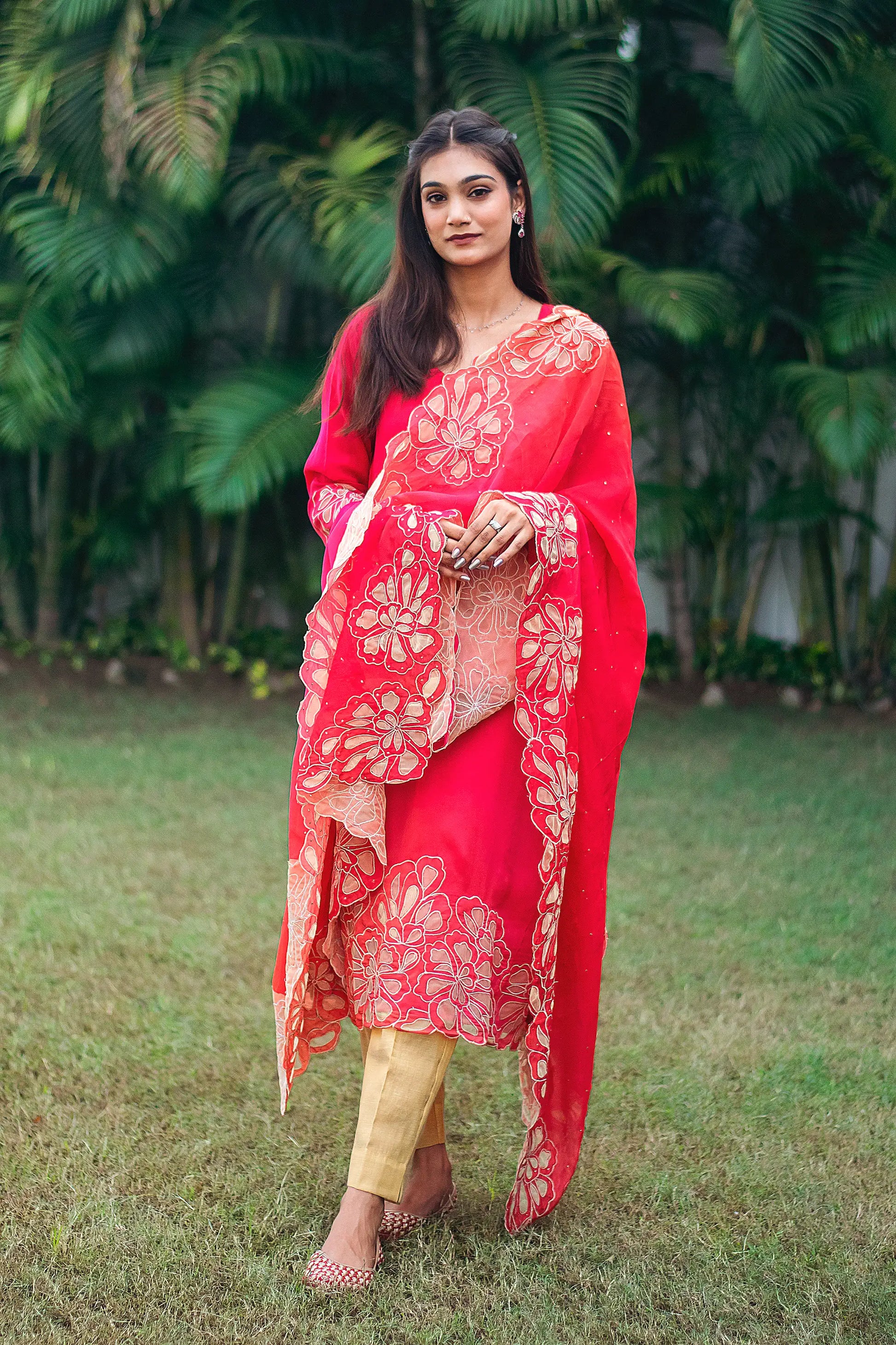 Indian model in a red organza kurta with gold cutwork, paired with a matching dupatta and gold trousers. 