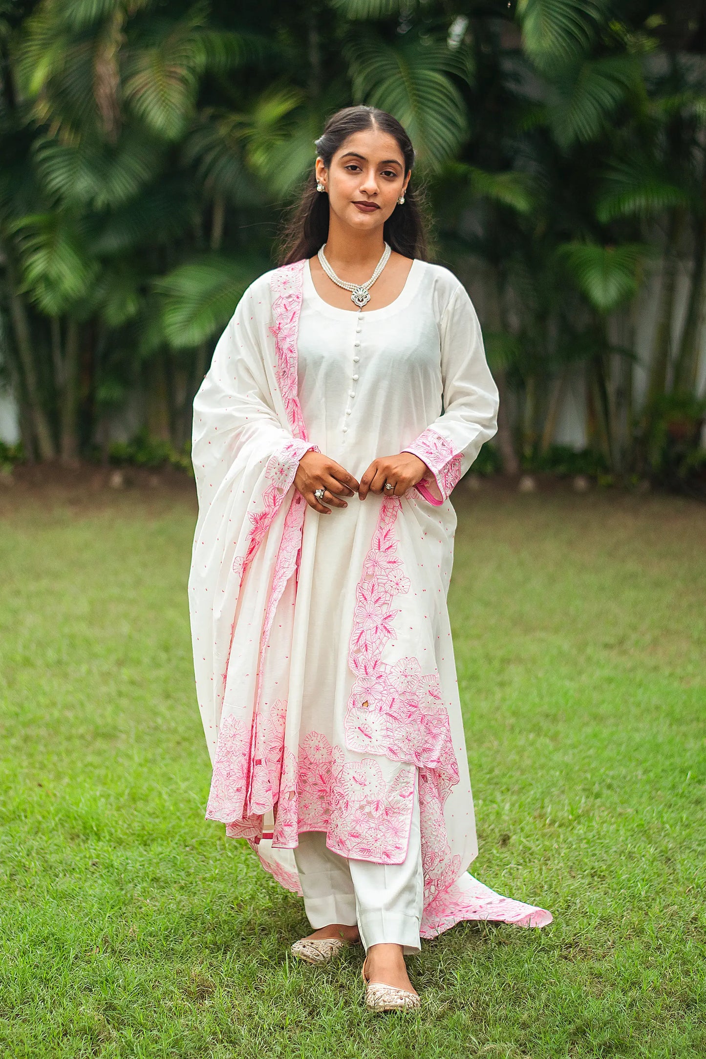 Indian model in an off-white chanderi kurta and dupatta with pink floral cutwork, paired with off-white trousers.